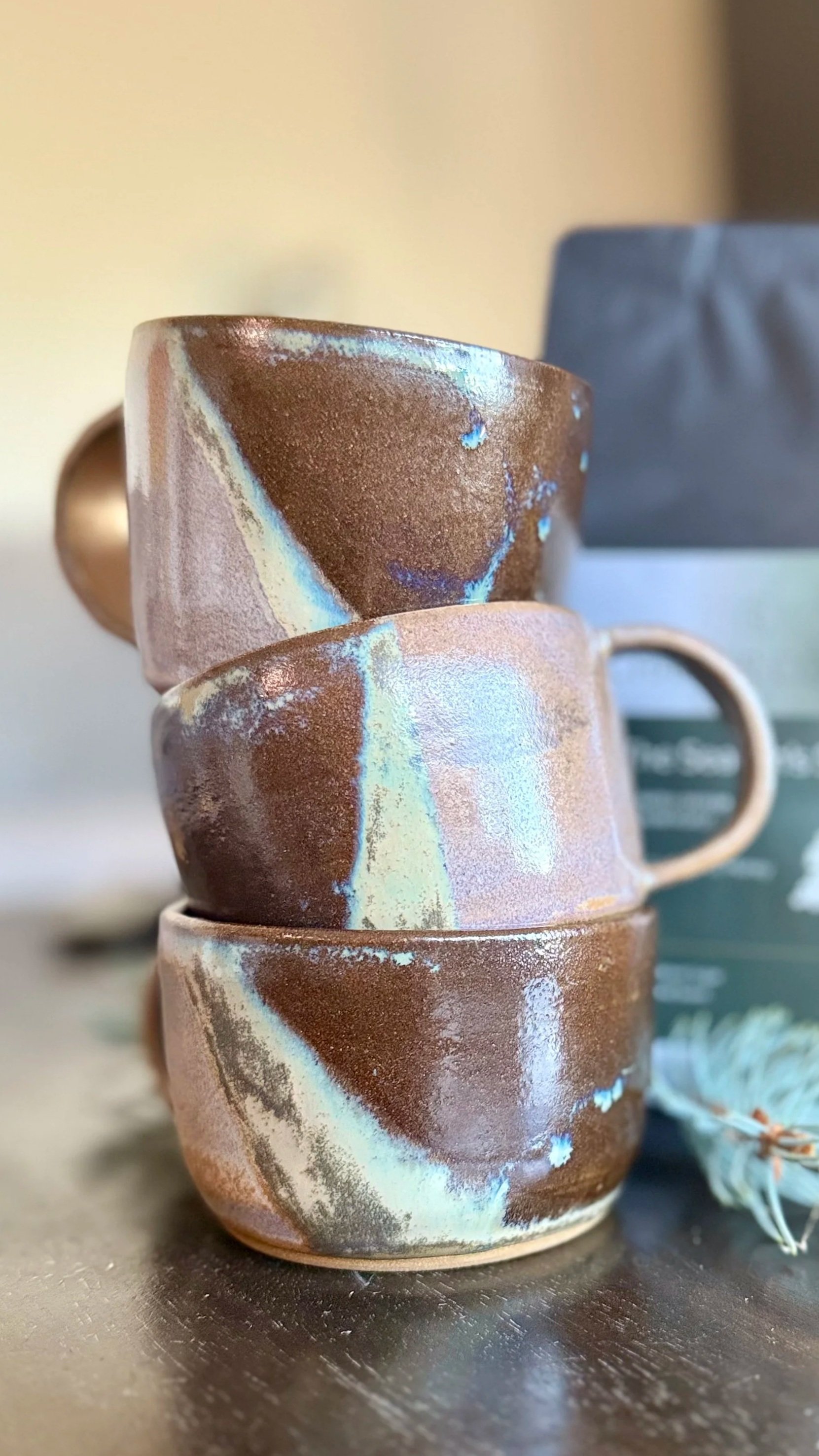 Stacked hand-thrown ceramic mugs from the Tinamarie Clayworks Studio × Chapter Coffee collaboration, highlighting form and craftsmanship