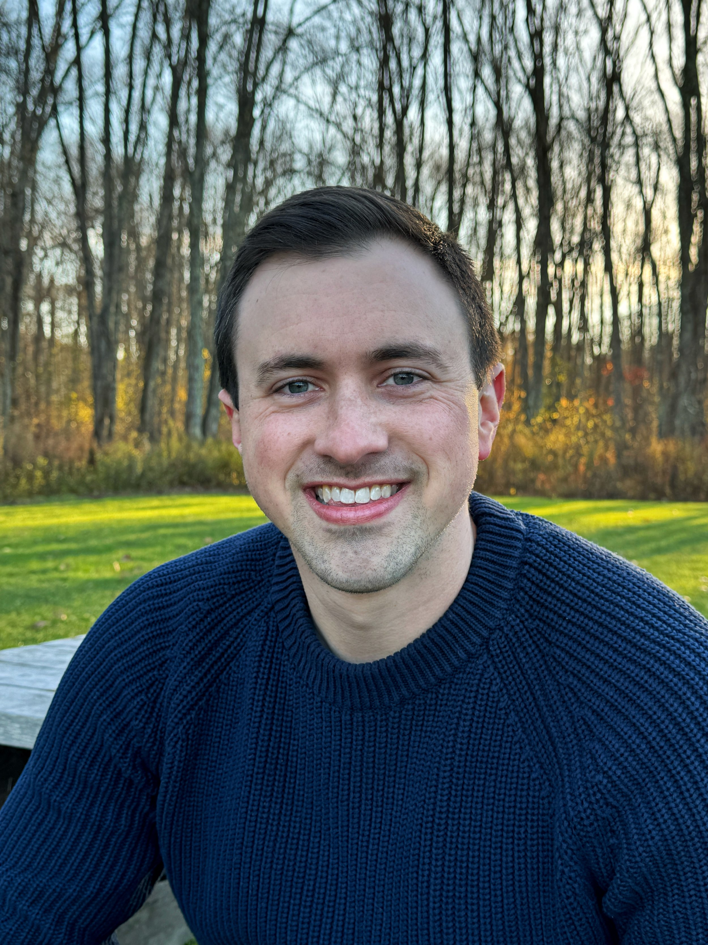 headshot of justin pomerenke in front of trees and green grass