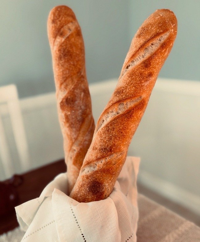 Two baguette bread sticks in a hand covered with a white napkin.