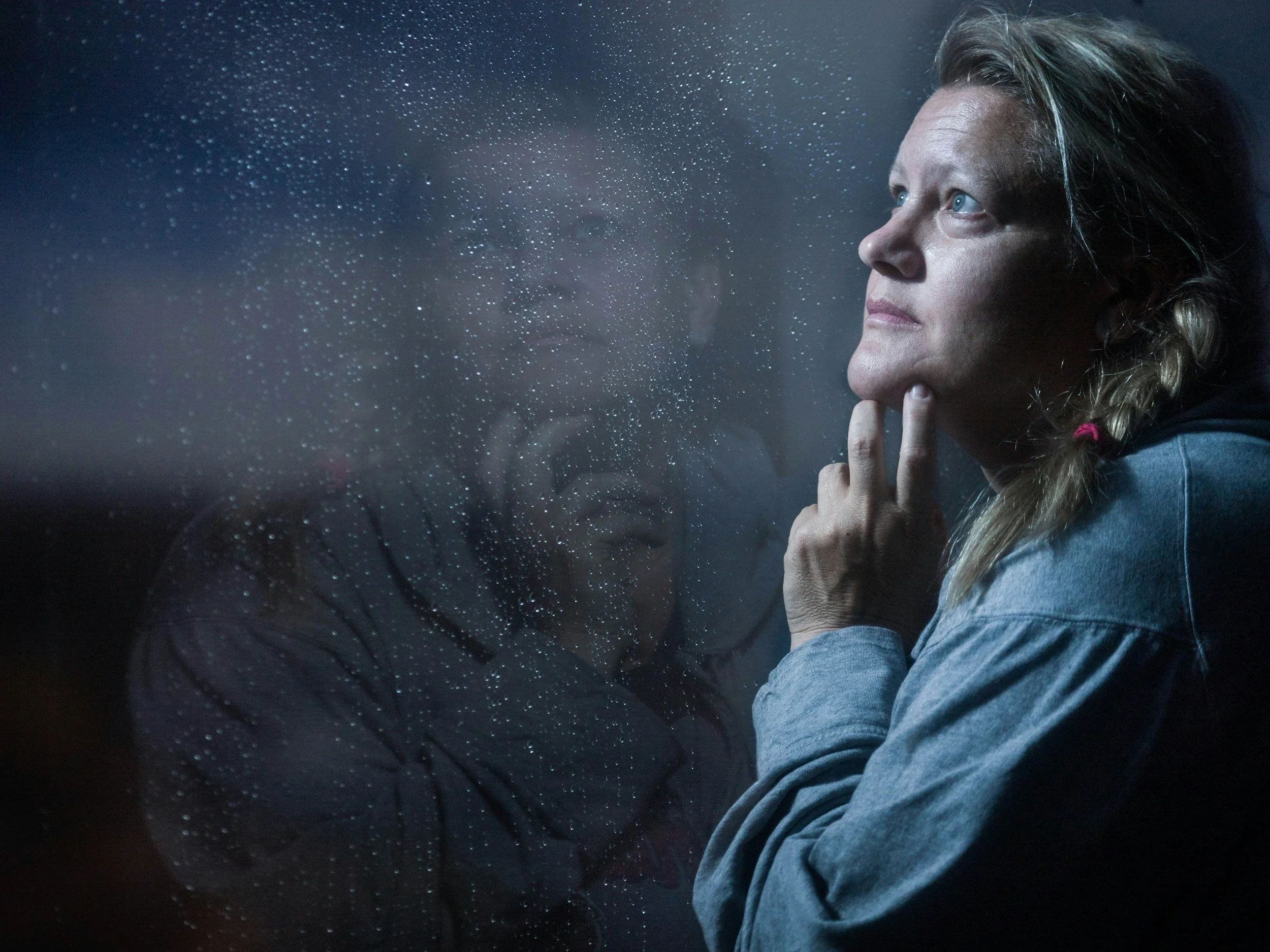 A woman looks sad out a window, representing the need for trauma informed therapy with Utah, Rhode Island, and Idaho therapist Amy Bowen.