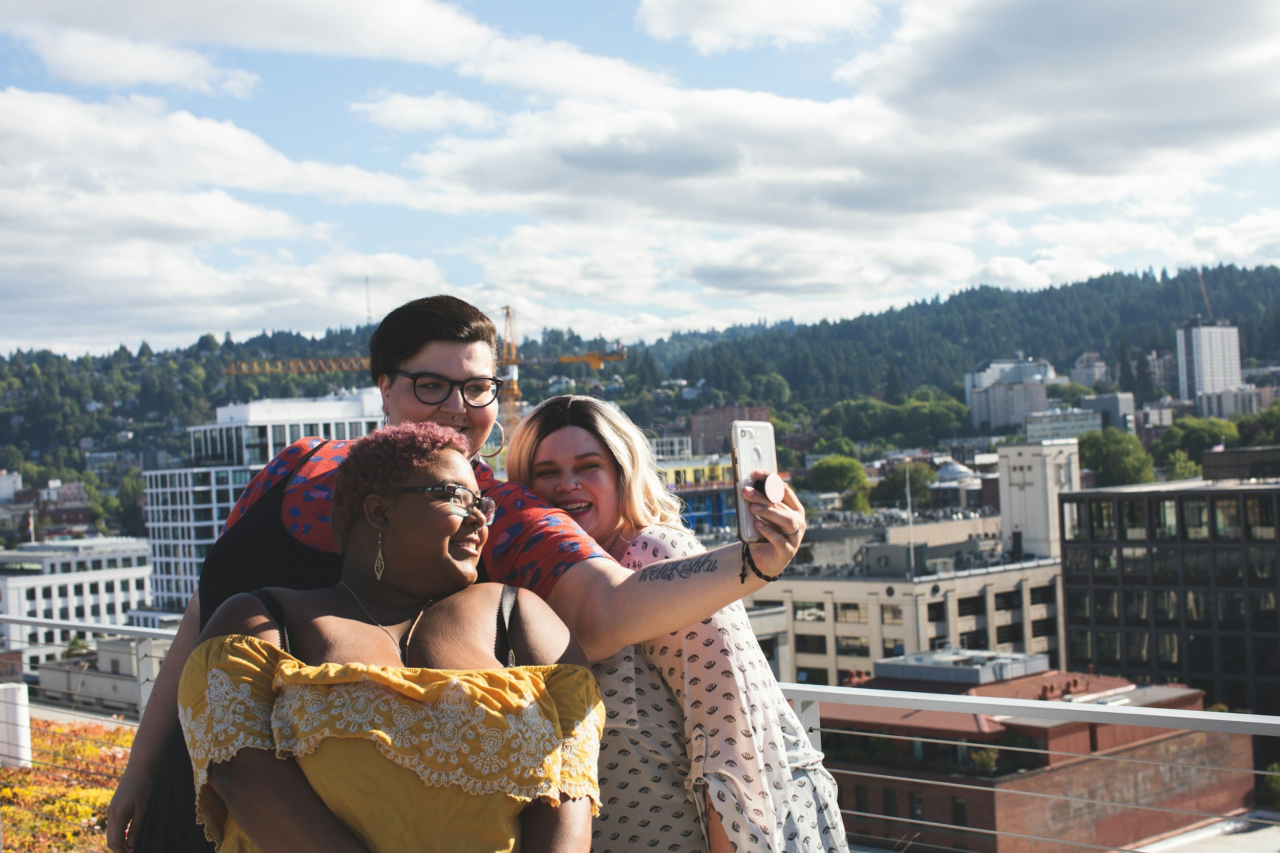 A diverse group of people taking a selfie on a rooftop at sunset; providing a safe space for LGBTQIA+ therapy in Utah, Idaho and Rhode Island.