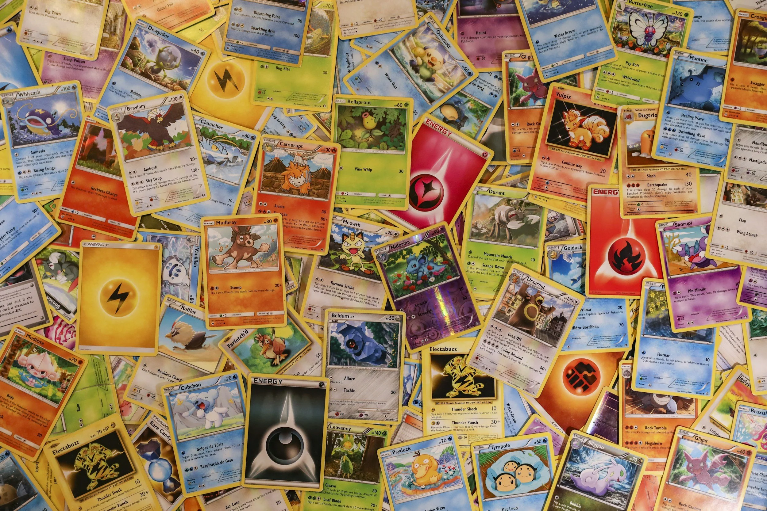 A scattered pile of colorful Pokémon trading cards; a "brain break" reflecting ADHD and autistic special interests.