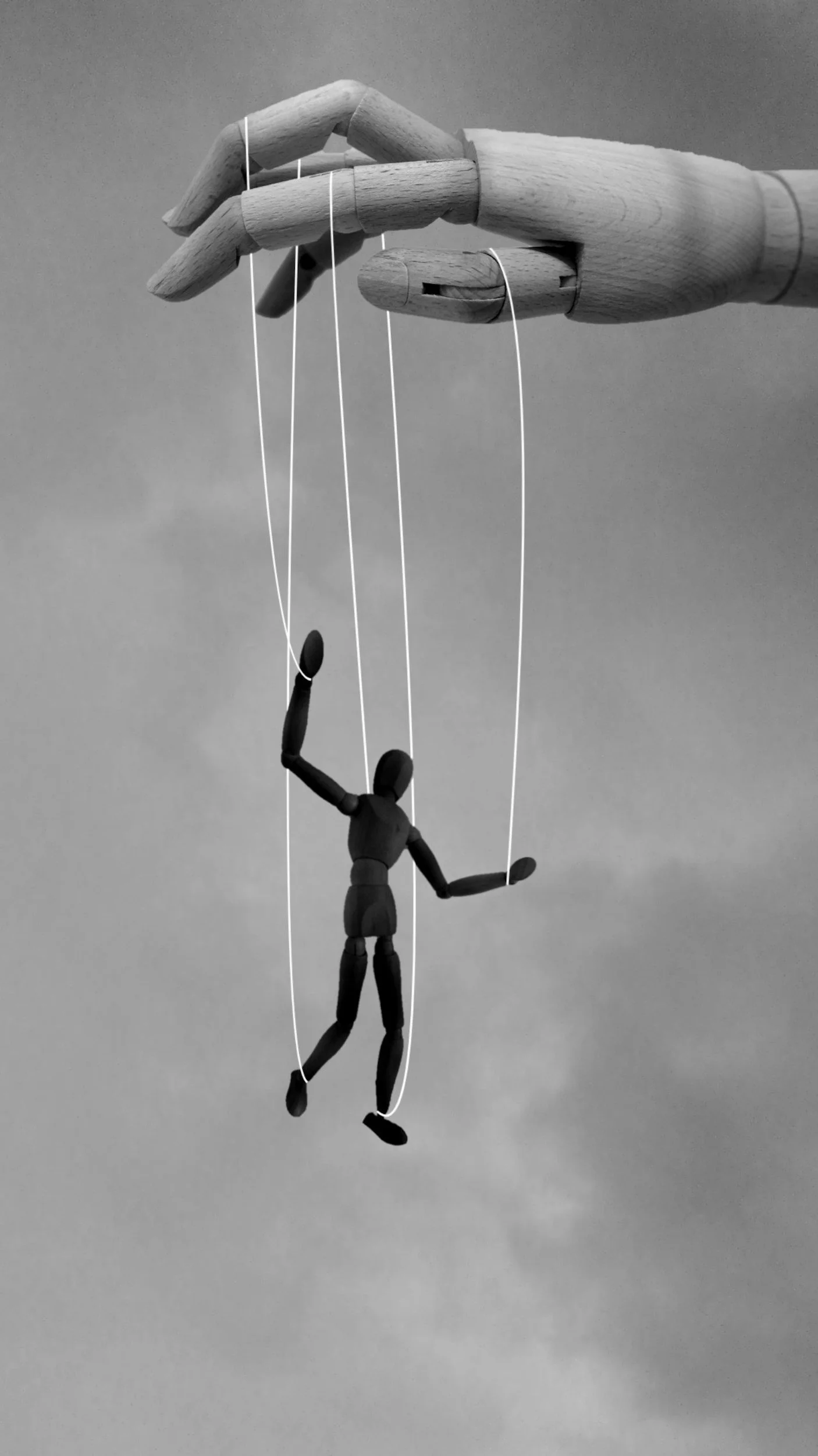 A hand holding up a wooden puppet by its strings; symbolizing the power dynamics, coercive control, and manipulation found in narcissistic and toxic relationships.