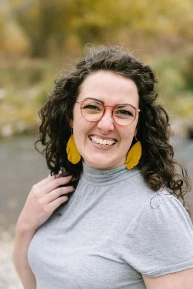 Amy Bowen - a therapist offering trauma informed therapy in Hyde Park Utah, Rhode Island, and Idaho -- smiles with bright earrings.