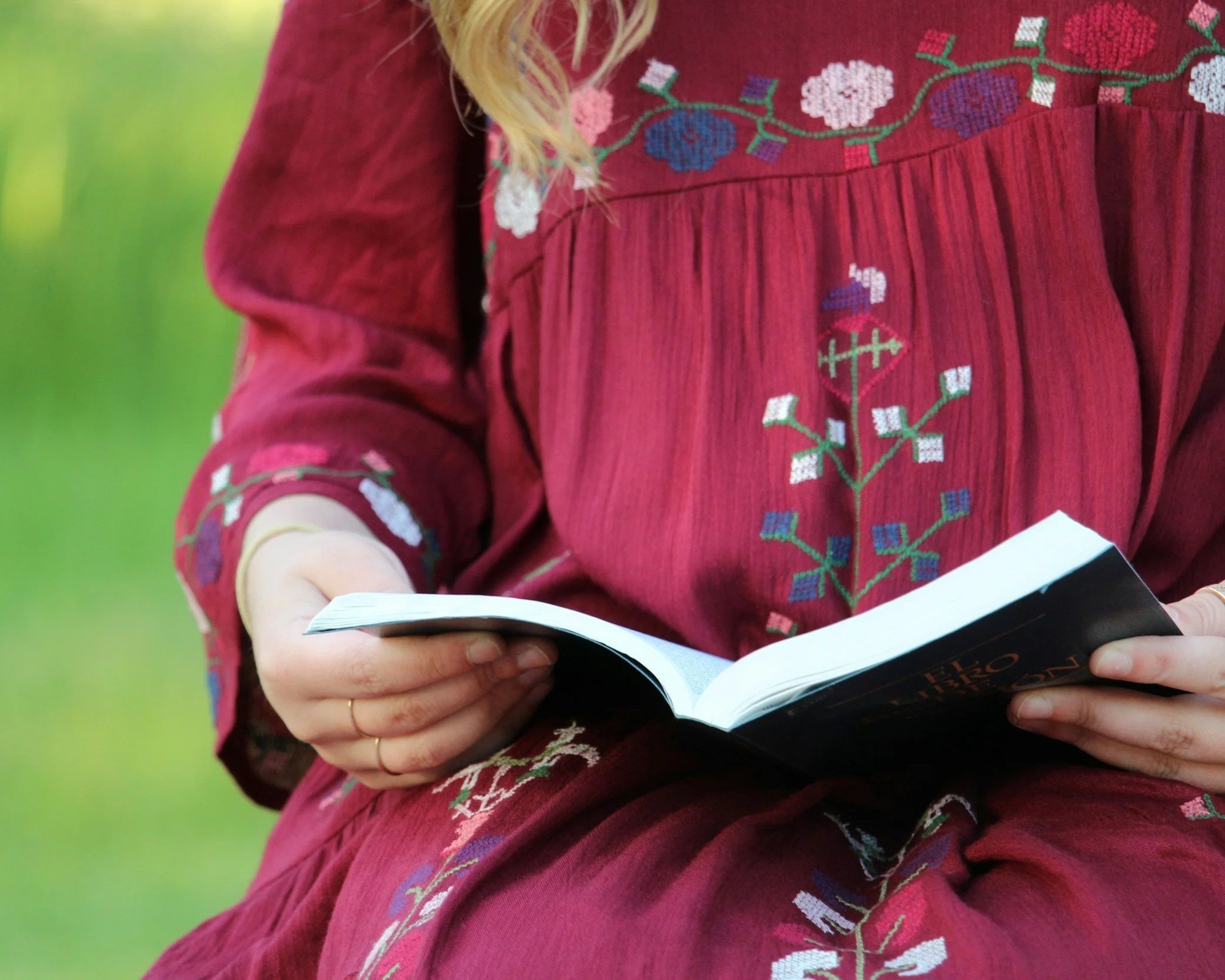 An individual in a pink dress holding an open religious book; processing the weight of scrupulosity and religious upbringing.