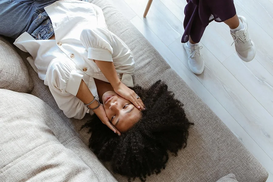 A woman lies on the floor looking upset, representing the need for trauma informed individual therapy with EMDR or IFS.