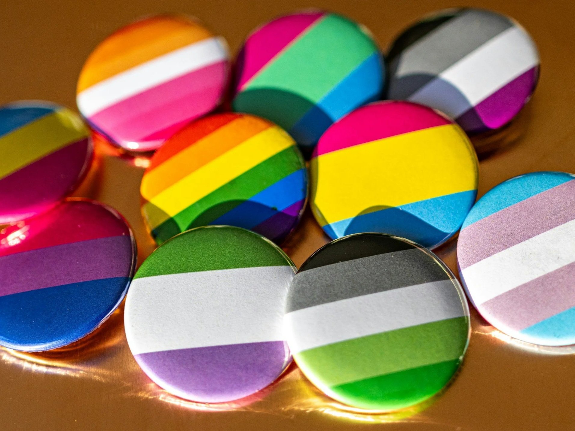 Various pins featuring LGBTQ+ pride flags and patterns; representing diverse identities and support for those seeking WPATH letters.