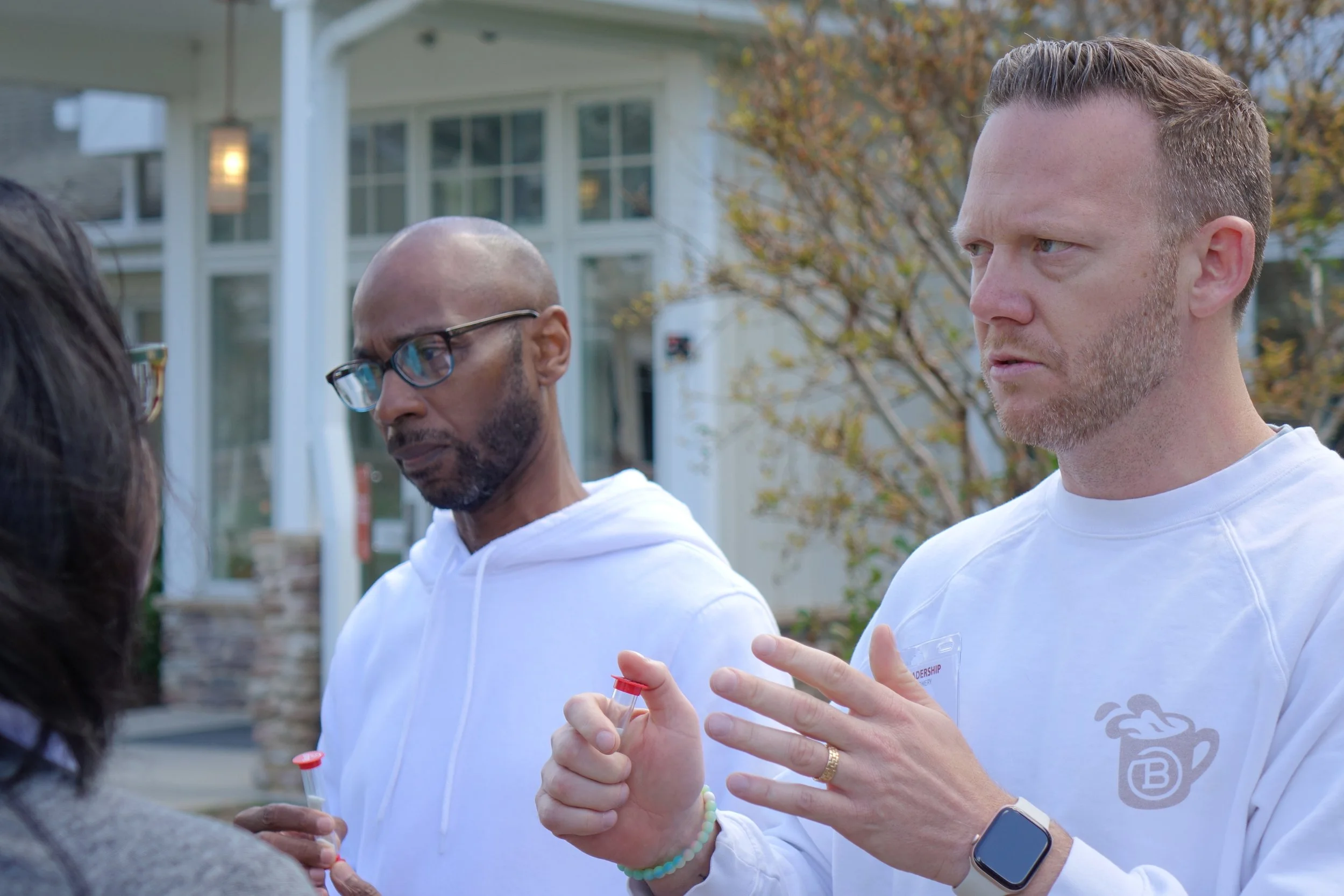 Two men side-by-side, engaging with their partners in serious conversations.