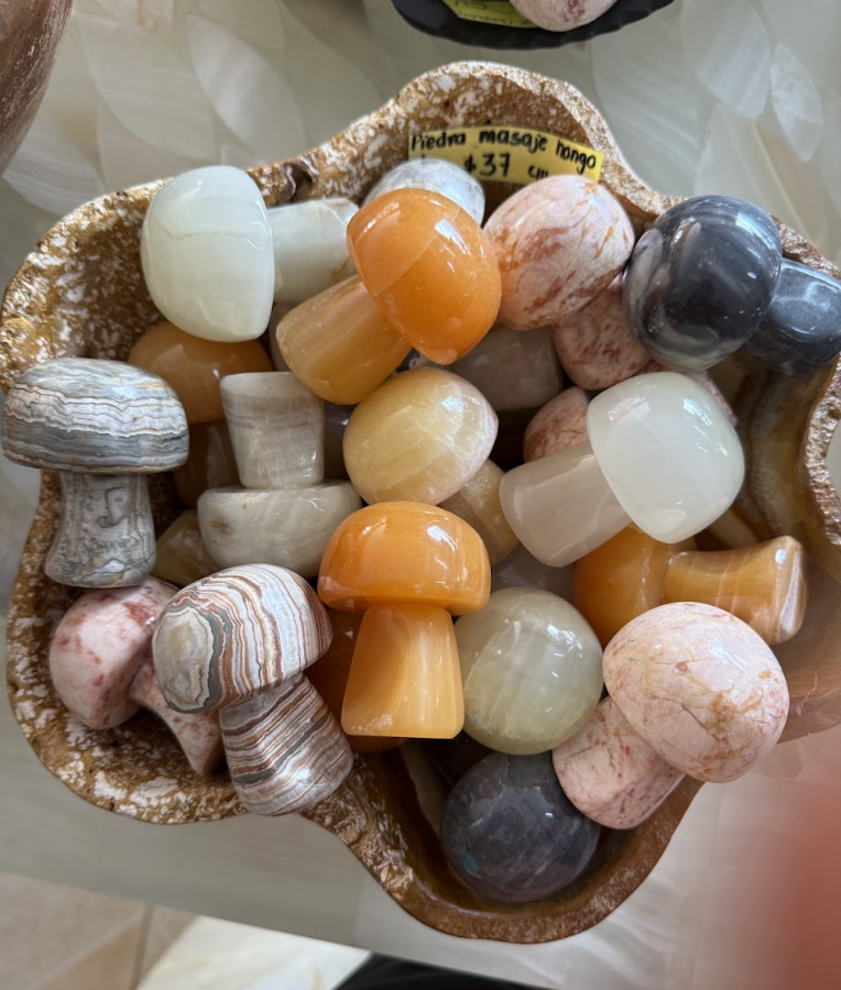 A decorative bowl filled with polished gemstone massage stones of various colors and patterns, including white, orange, gray, and pink.