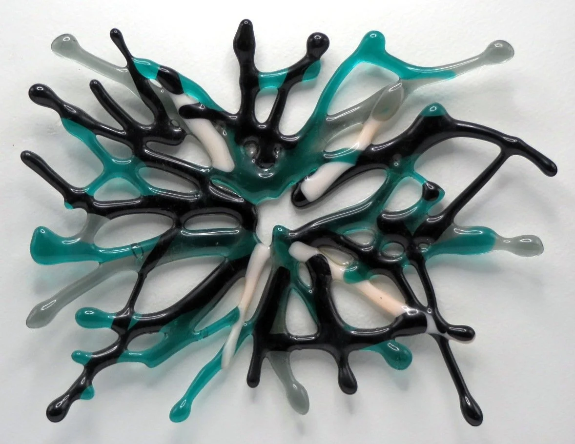 Slightly curved abstract fused glass art sculpture with black, cream and emerald colors.