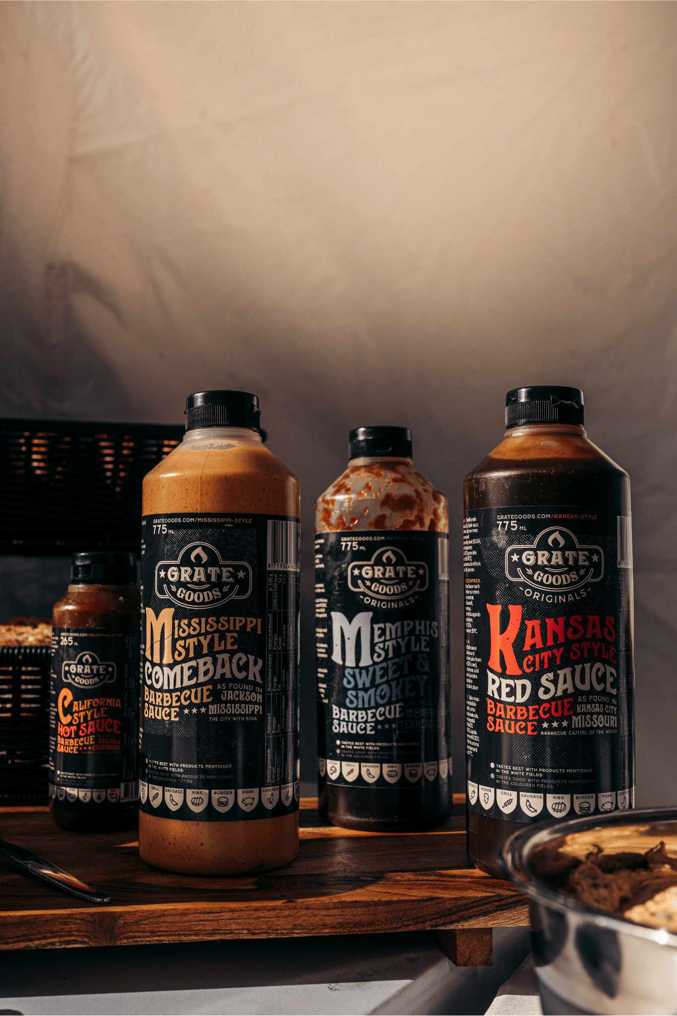 Verschillende barbecuesauzen op een houten tafel, met etiketten zoals Mississippi Style, Memphis Style, en Kansas City Style.