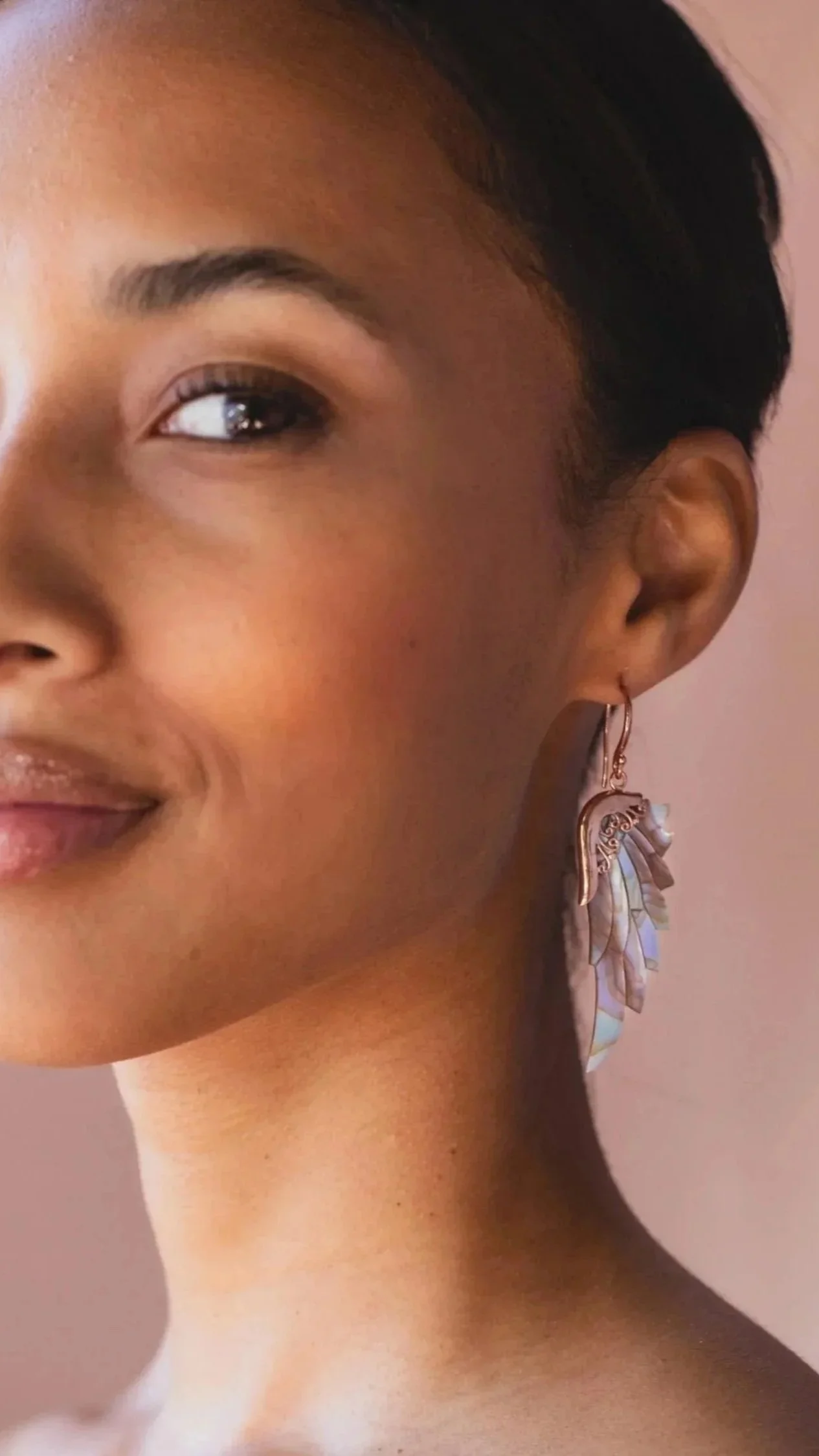 Close-up of a woman's face with a half-smile, featuring an ornate earring on her ear.