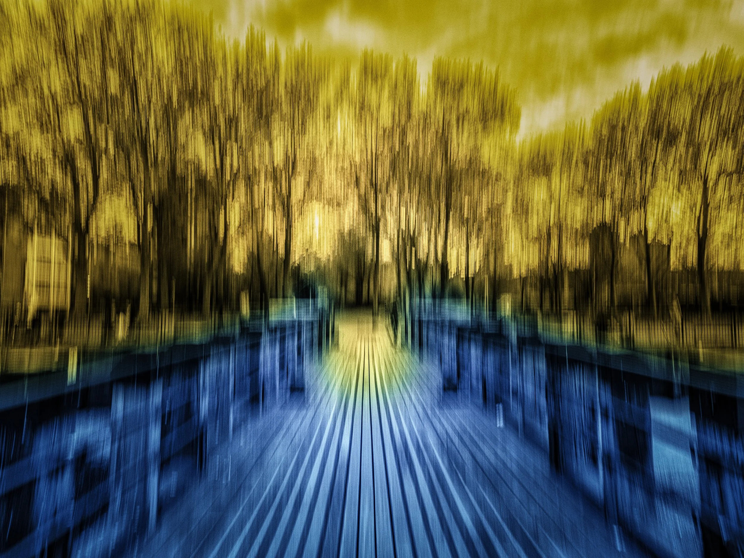 Eternal Roundabout – Duotone abstract ICM photograph of a Thames pier with glowing golden trees and indigo tones, blending motion, subtle grain, warmth, and stillness.