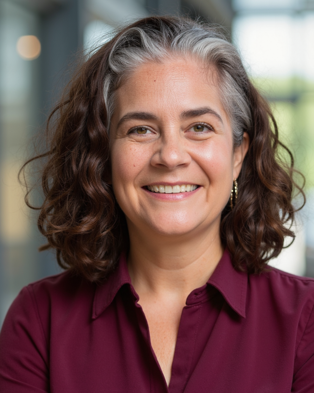 A smiling woman in her 50's with curly salt and pepper hair..