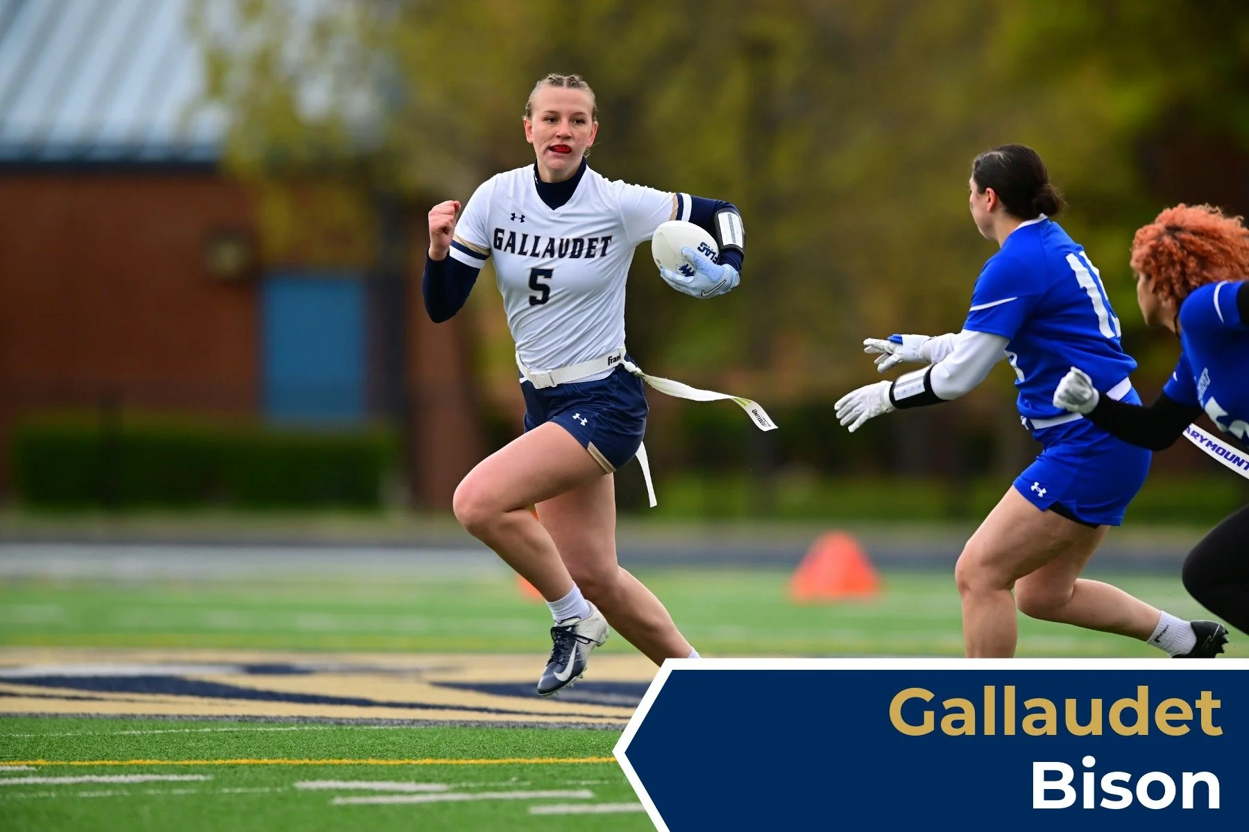 A female soccer player running with a ball during a game, wearing a white Galludet jersey with the number 5, and being chased by female opponents in blue jerseys.