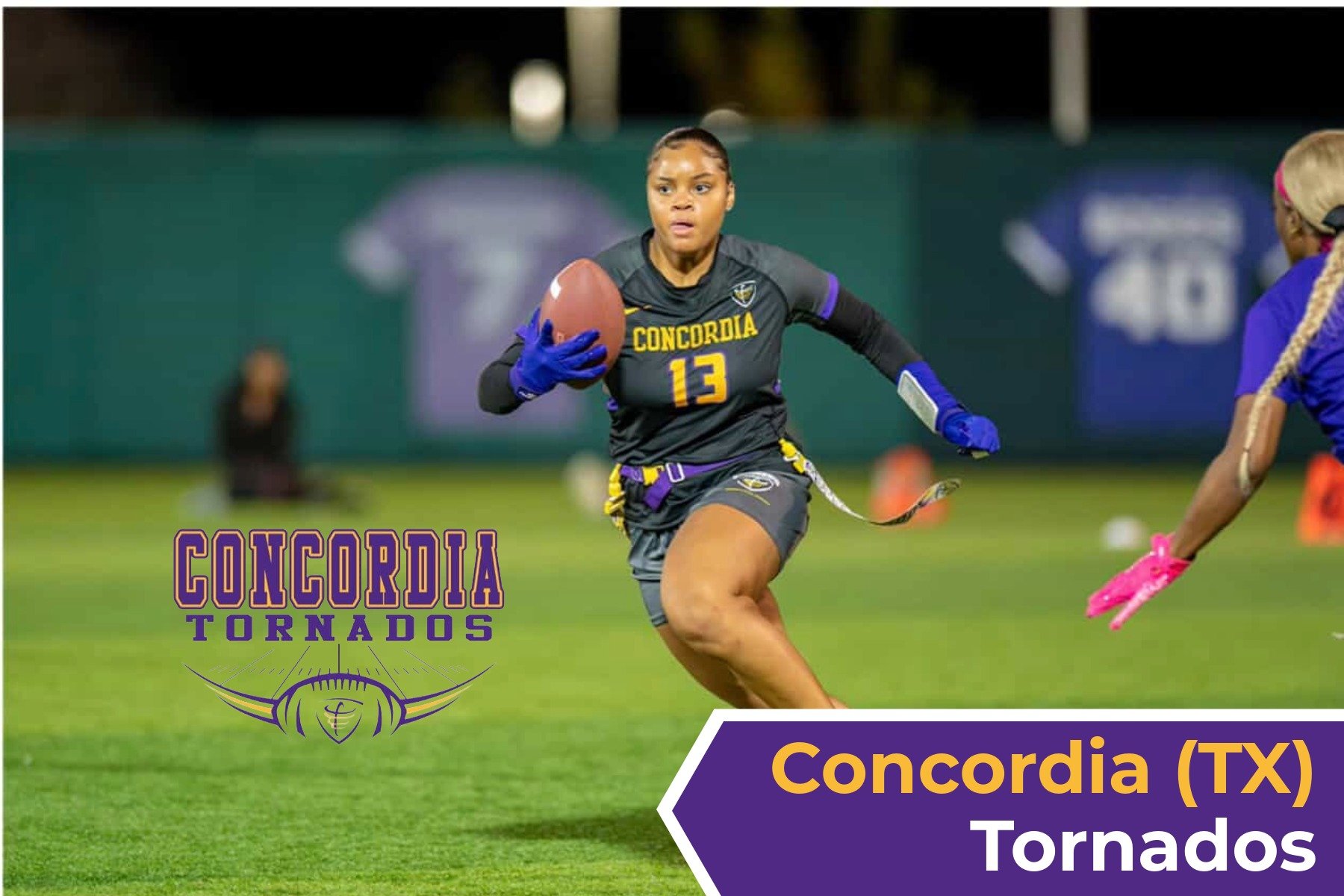 A woman football player from Concordia Tornados wearing a black uniform with yellow and purple accents, holding a football while running on the field during a game. The background shows a blurred football field and team logo.