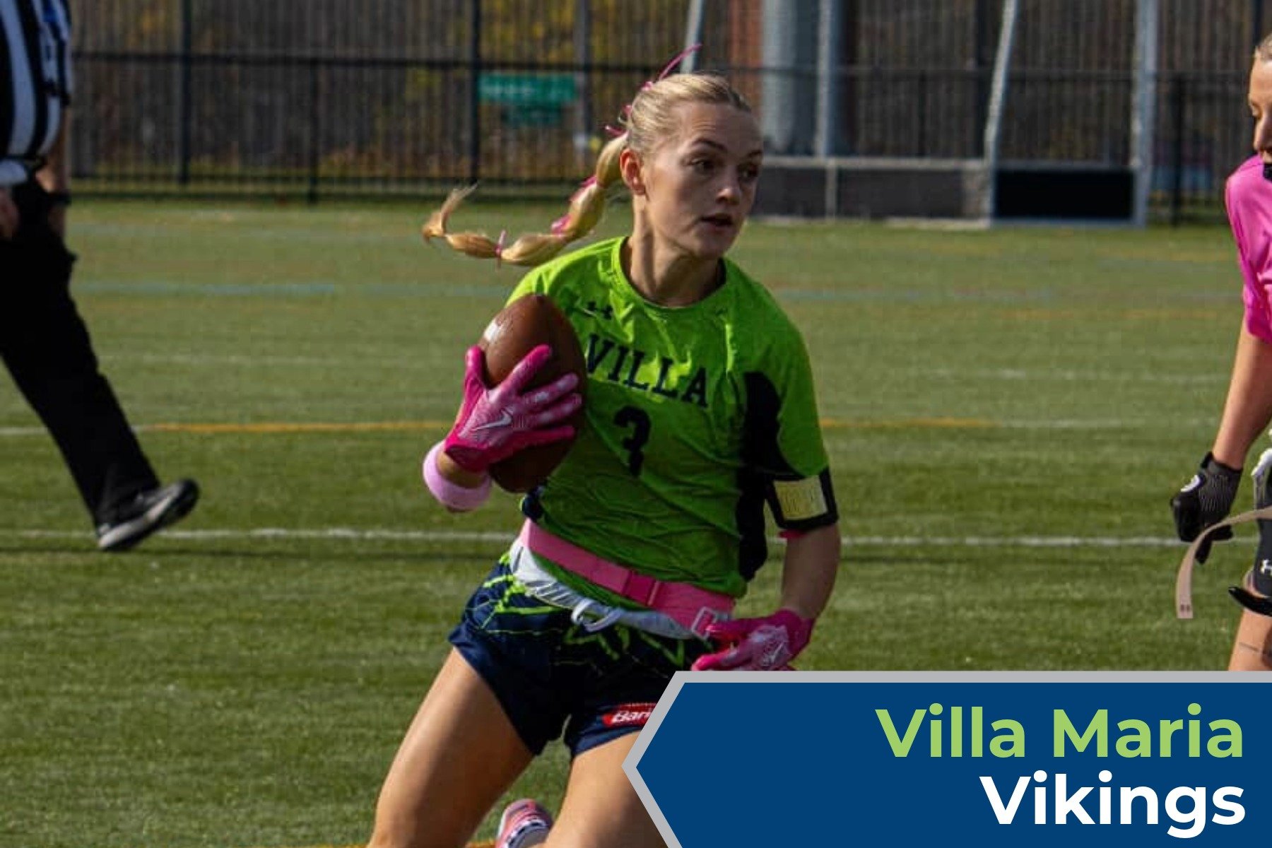 A female football player in a green jersey holding a football on a field during a game.