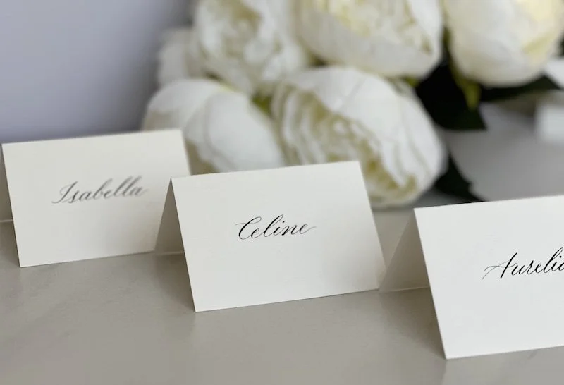 Set of custom hand-written modern calligraphy place cards for wedding guests on cream paper