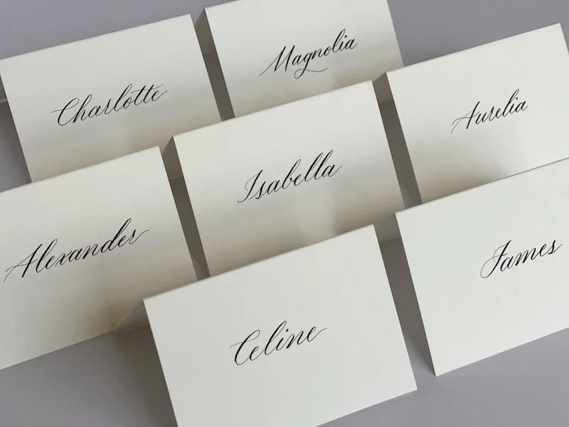 Set of custom hand-written modern calligraphy place cards for wedding guests on cream paper