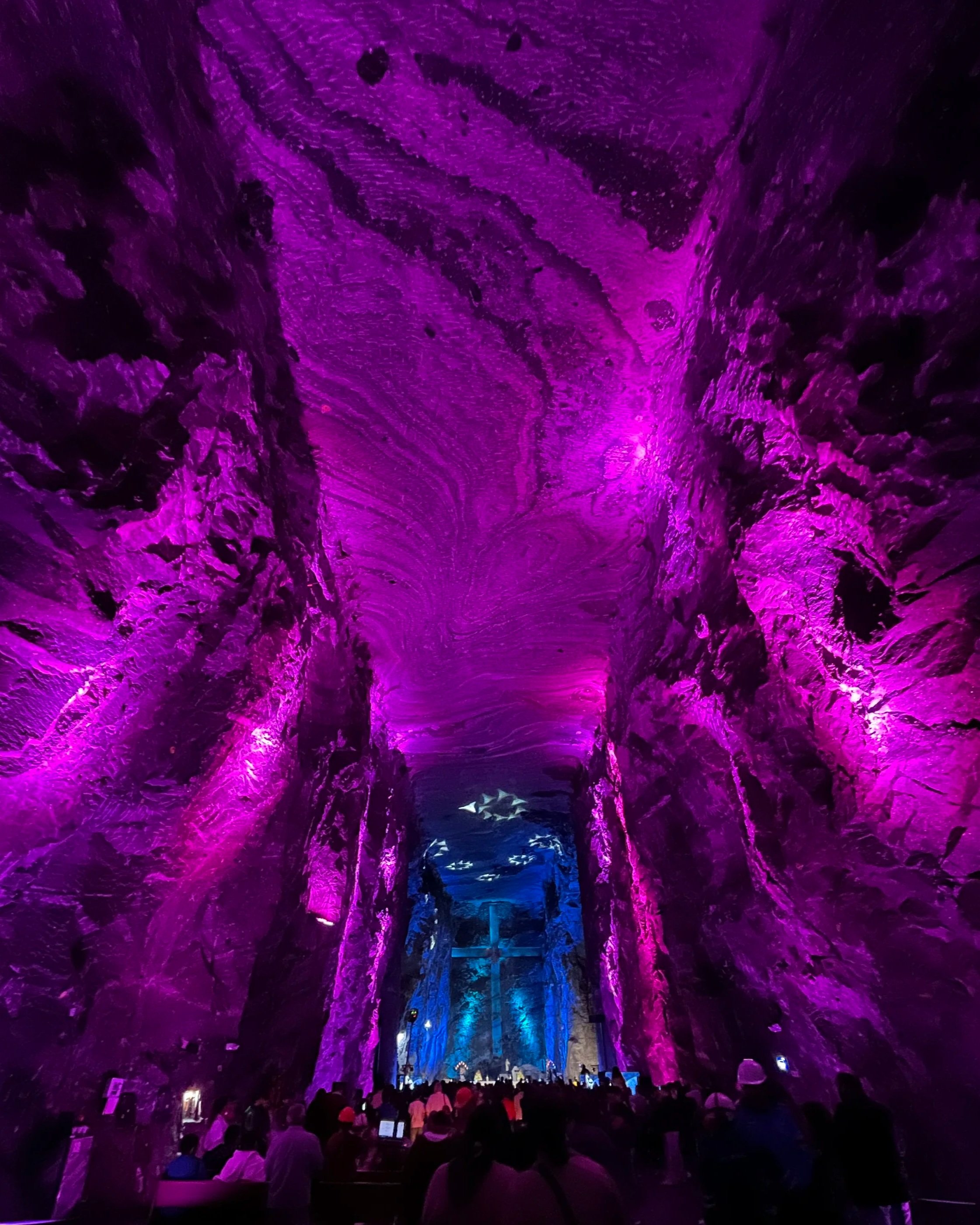 Underground cave with purple and blue lighting and a crowd of people.