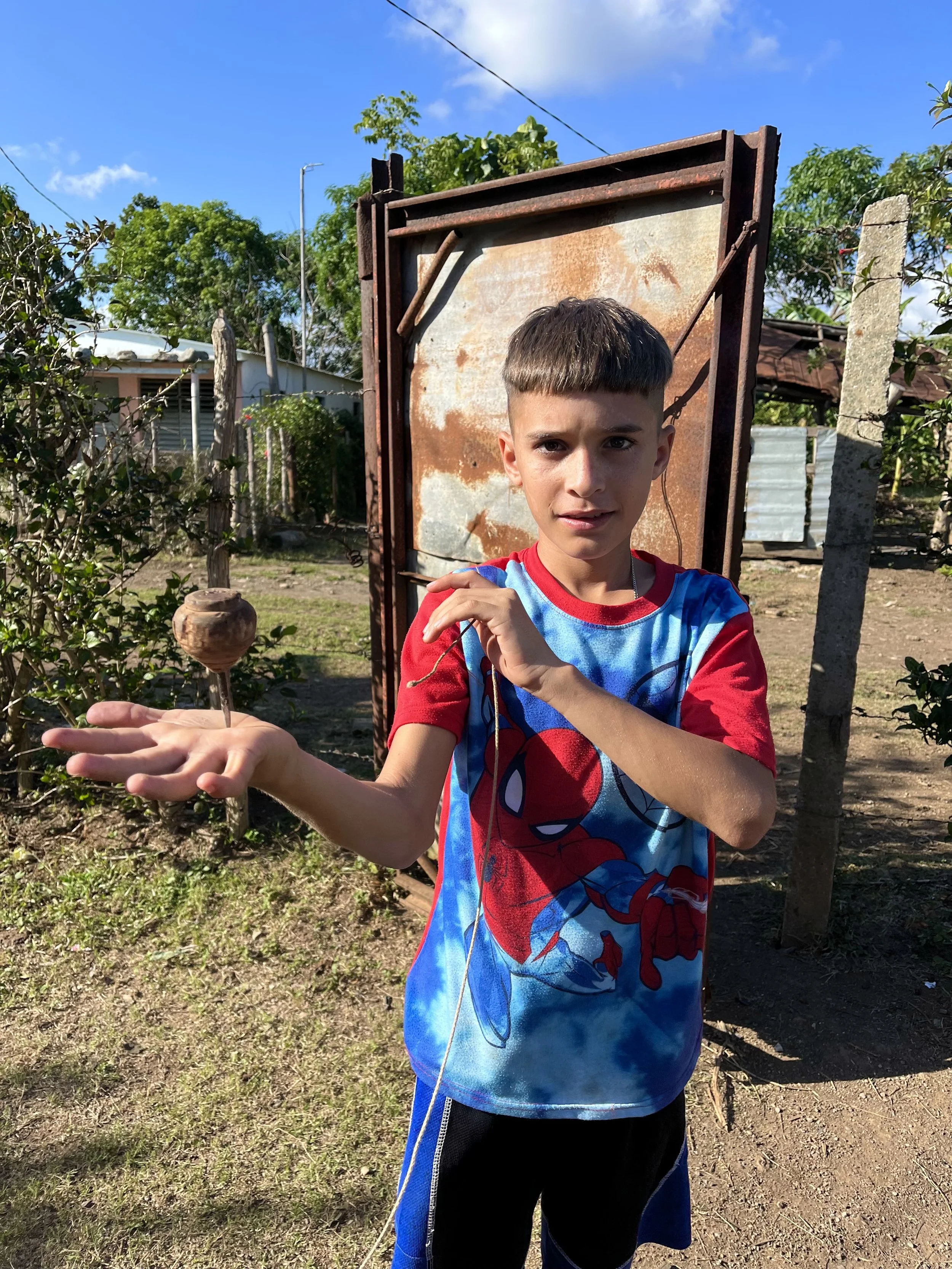 Boy in Spider-Man shirt holding a bird's nest outdoors.