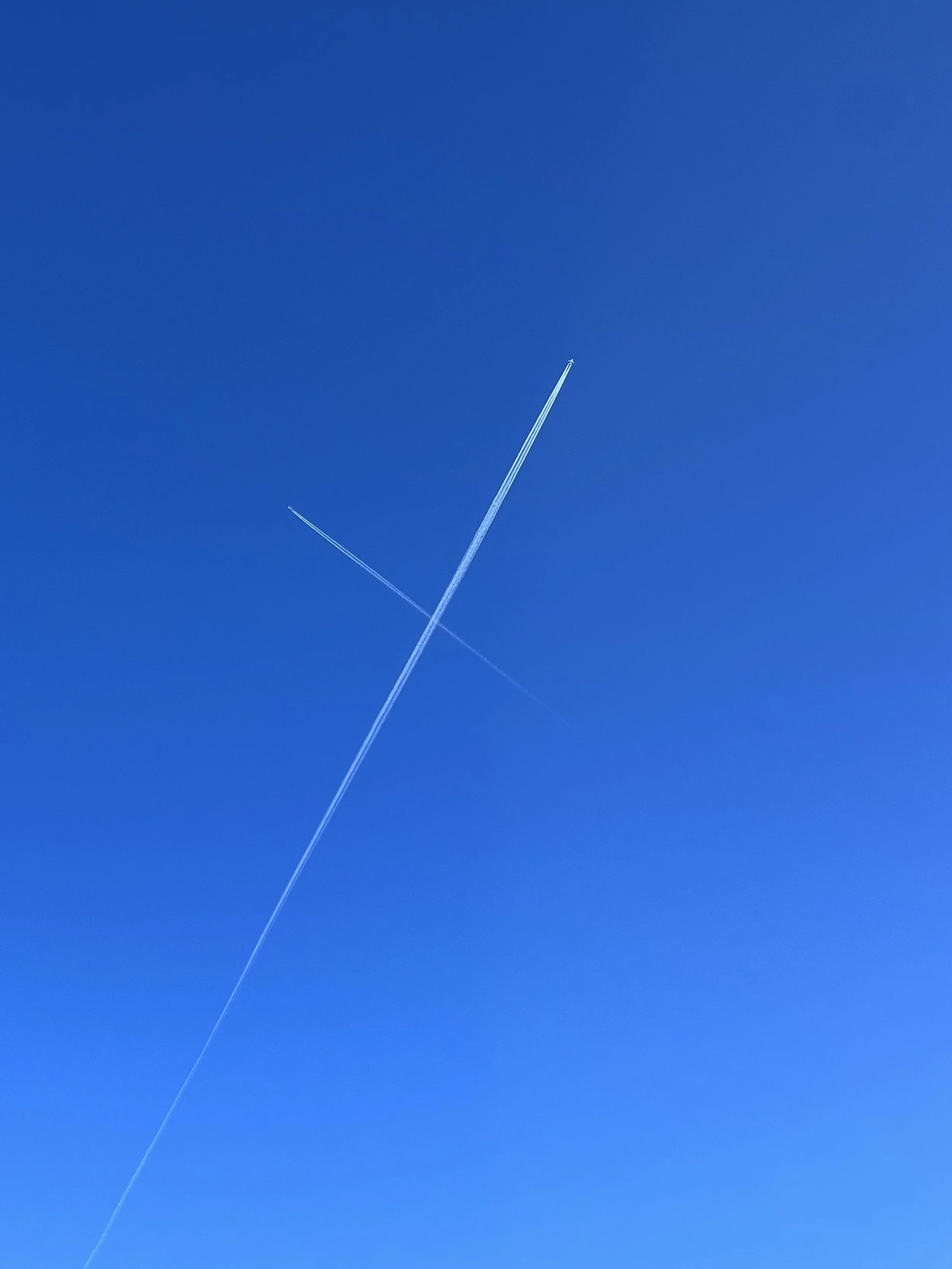 Blue sky with intersecting contrails