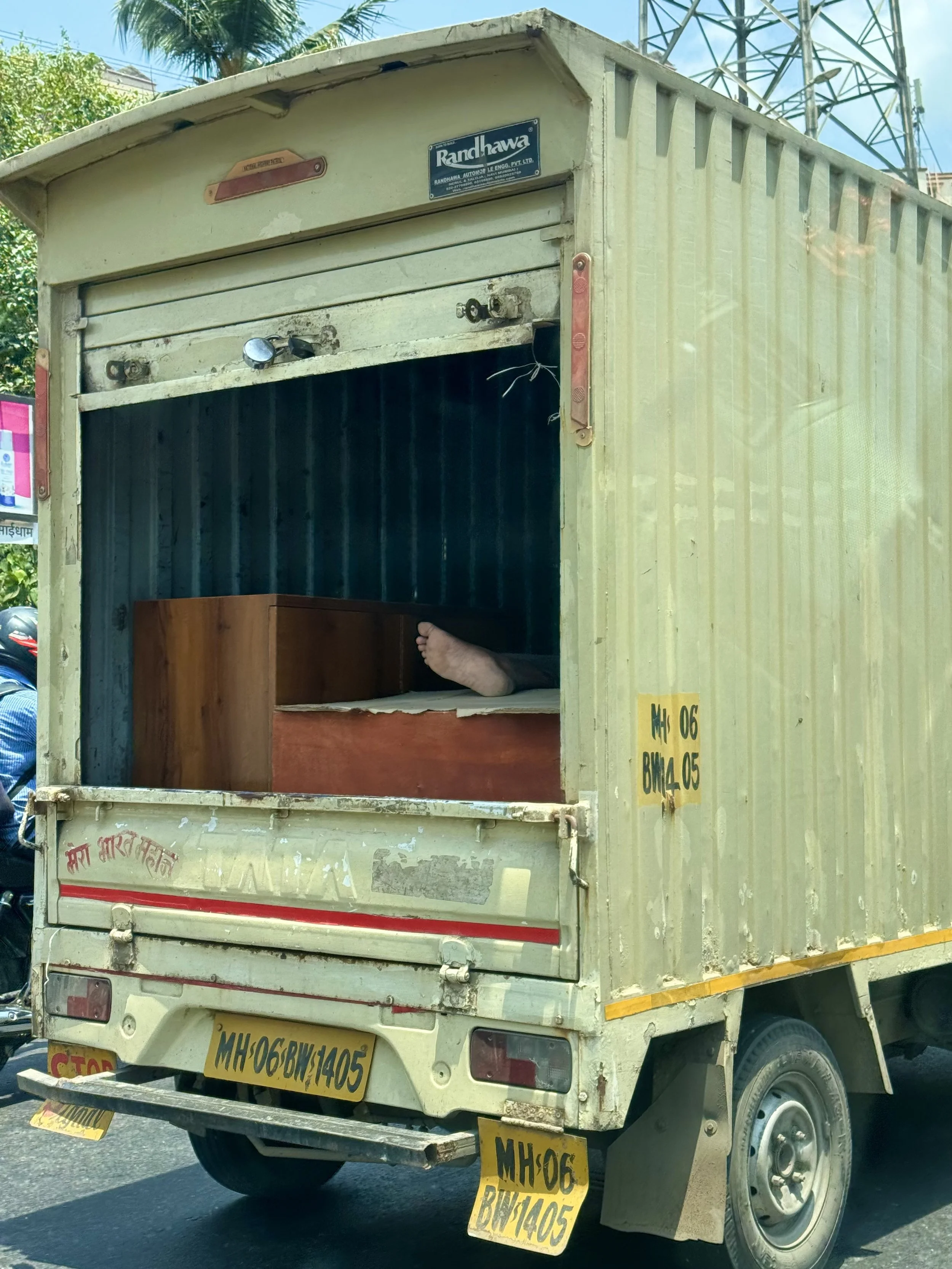 Truck on road with rear door open, showing human feet inside.