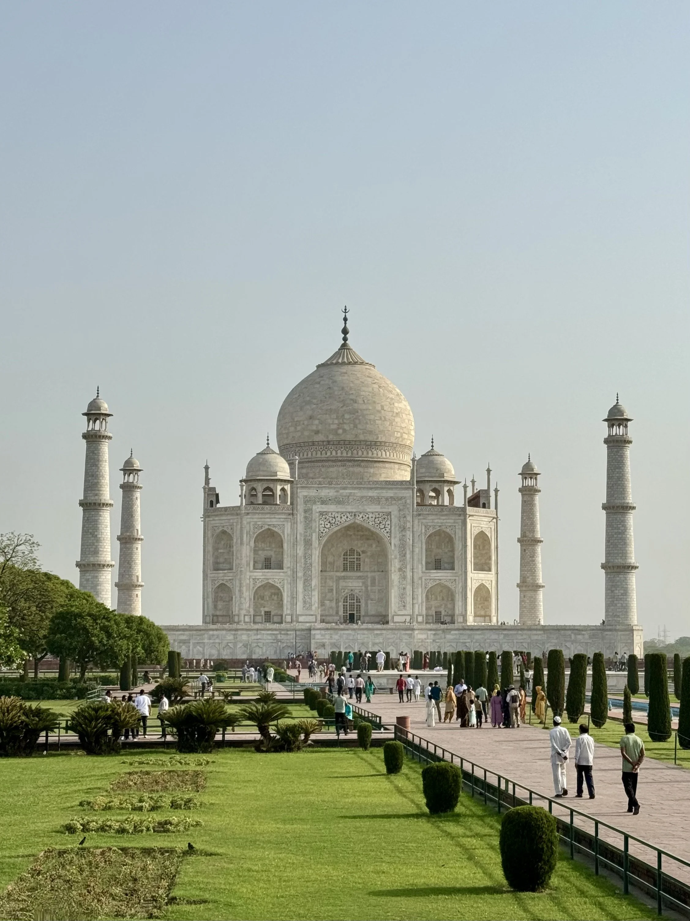 The Taj Mahal in Agra, India, with gardens and tourists in the foreground.