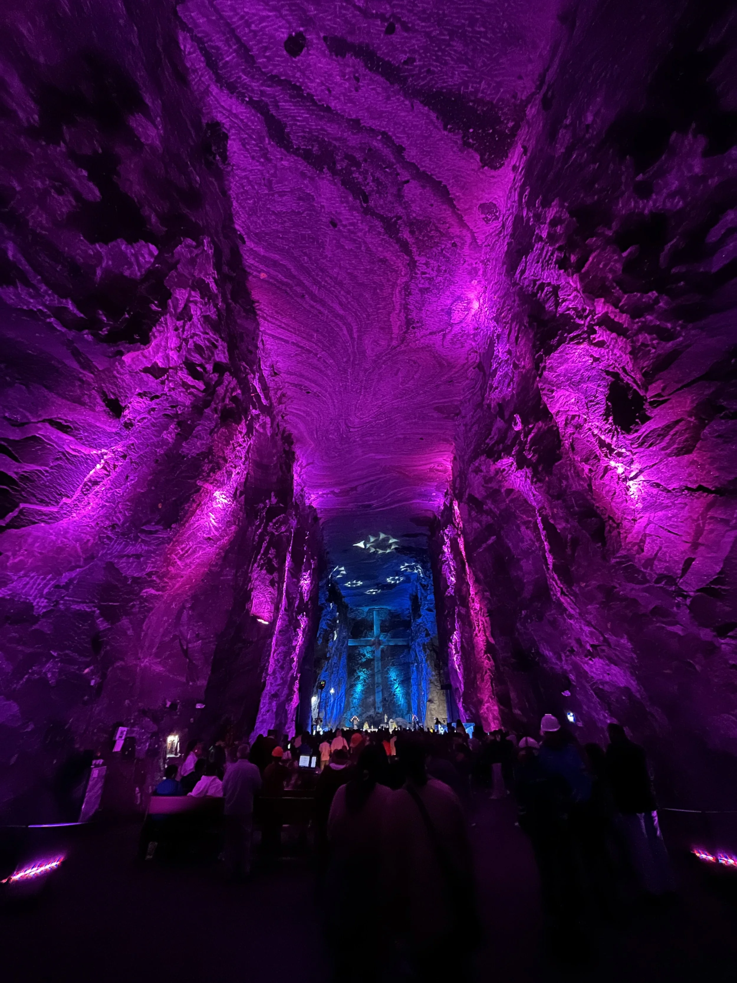 Underground cave with purple and blue lighting and a crowd of people.