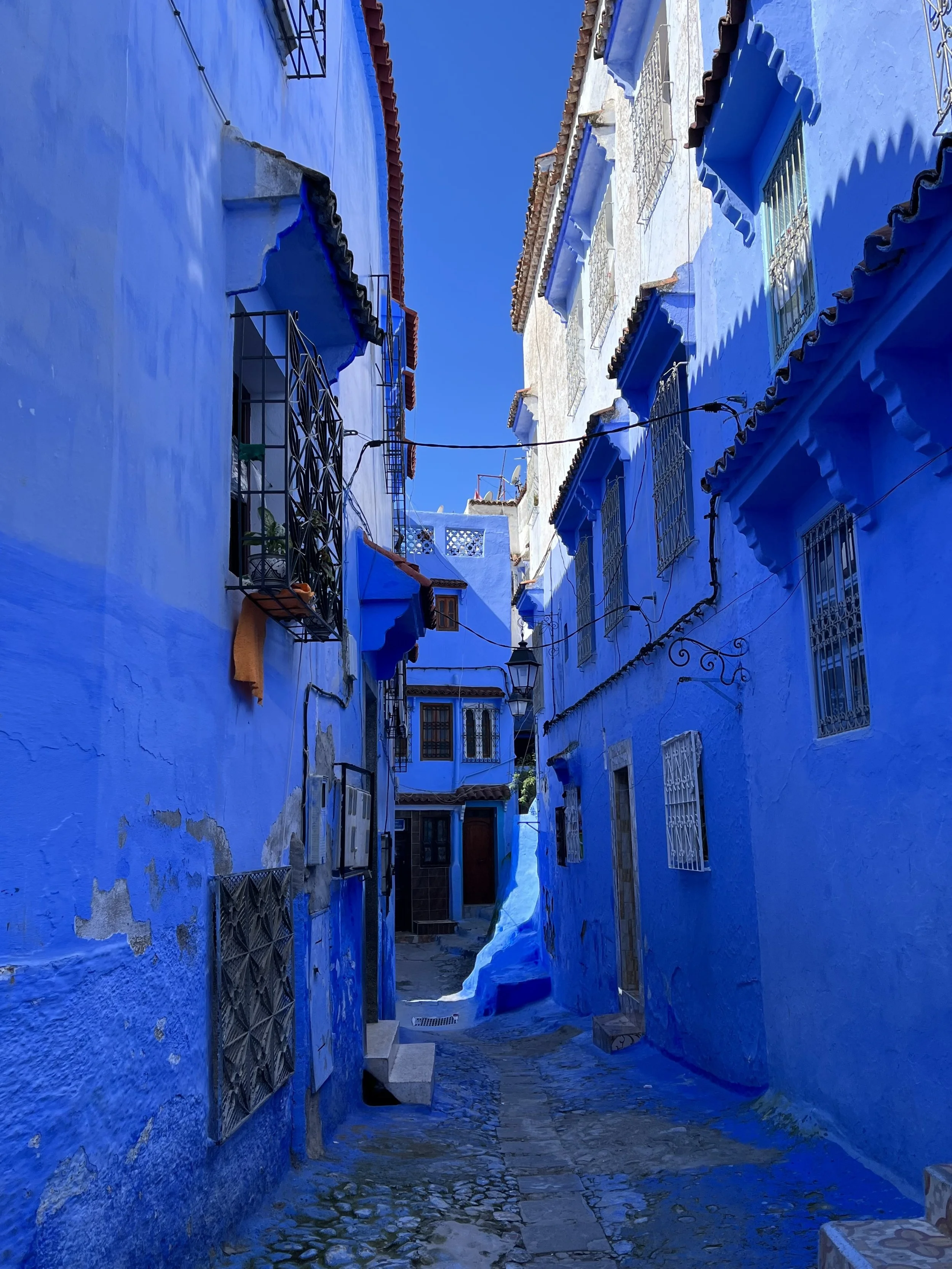 Narrow alley with blue-painted buildings in Chefchaouen, Morocco.