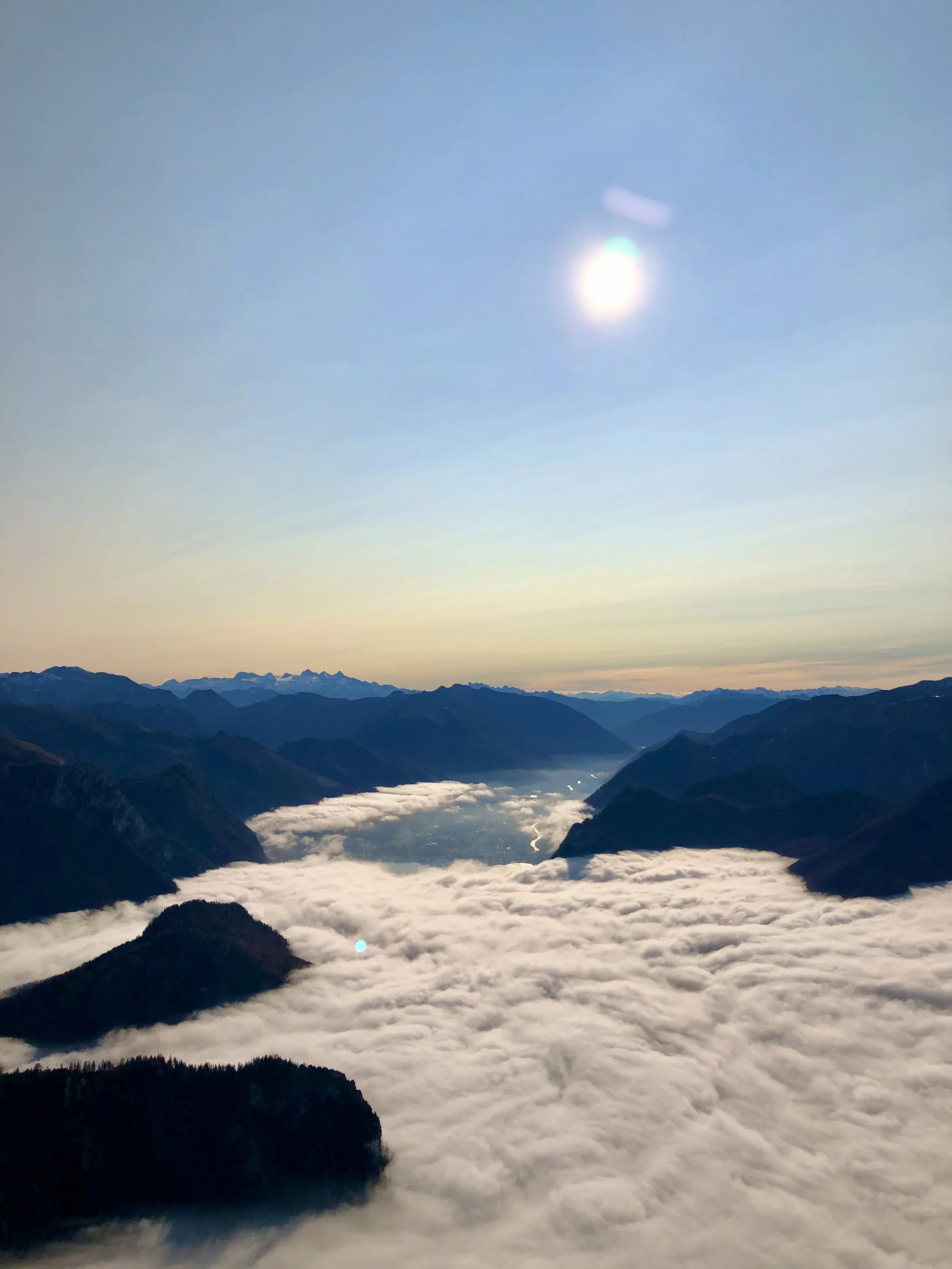 Mountain landscape with clouds beneath a bright sun.