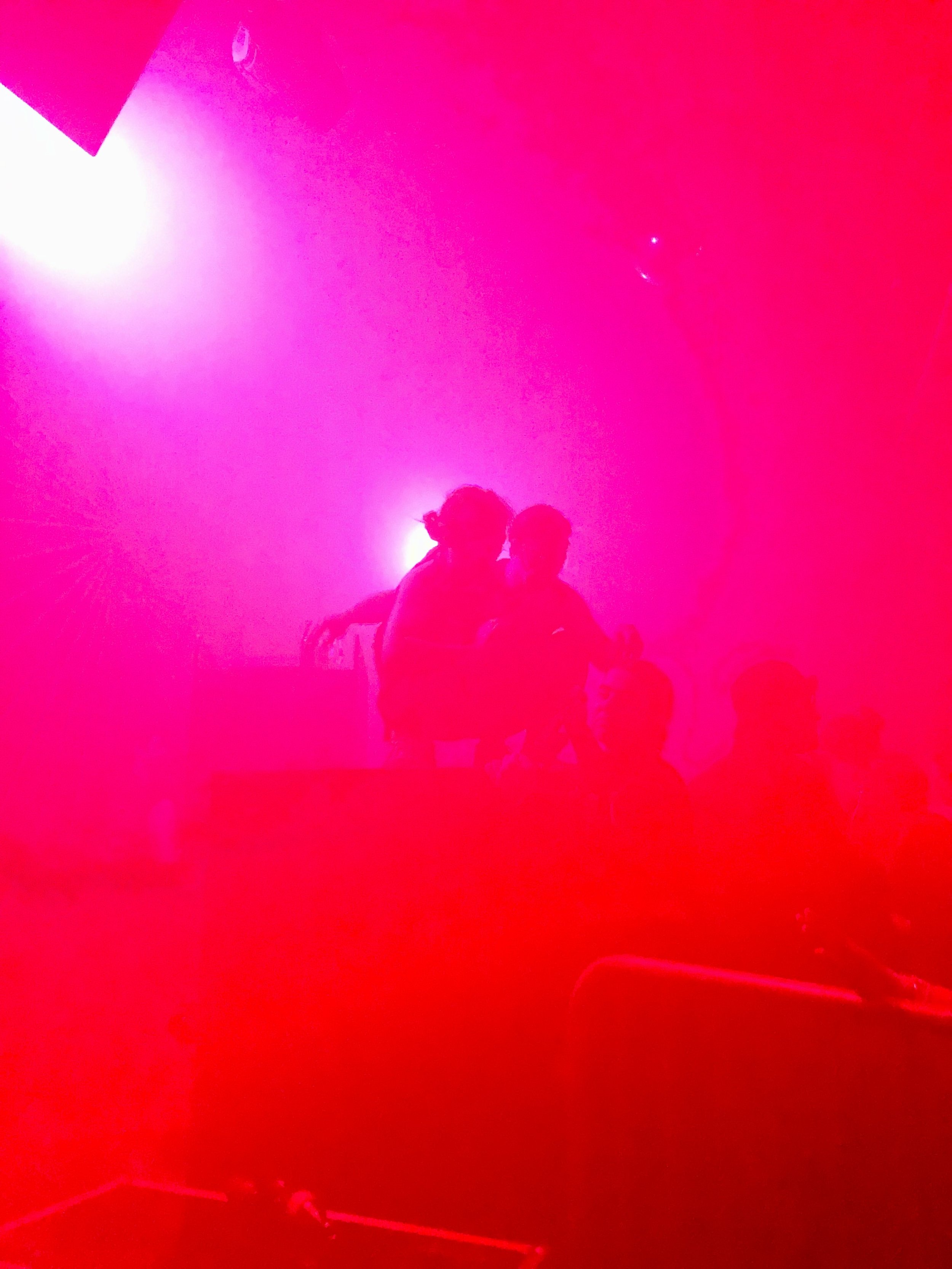 Silhouetted people in a dark room with intense red lighting.