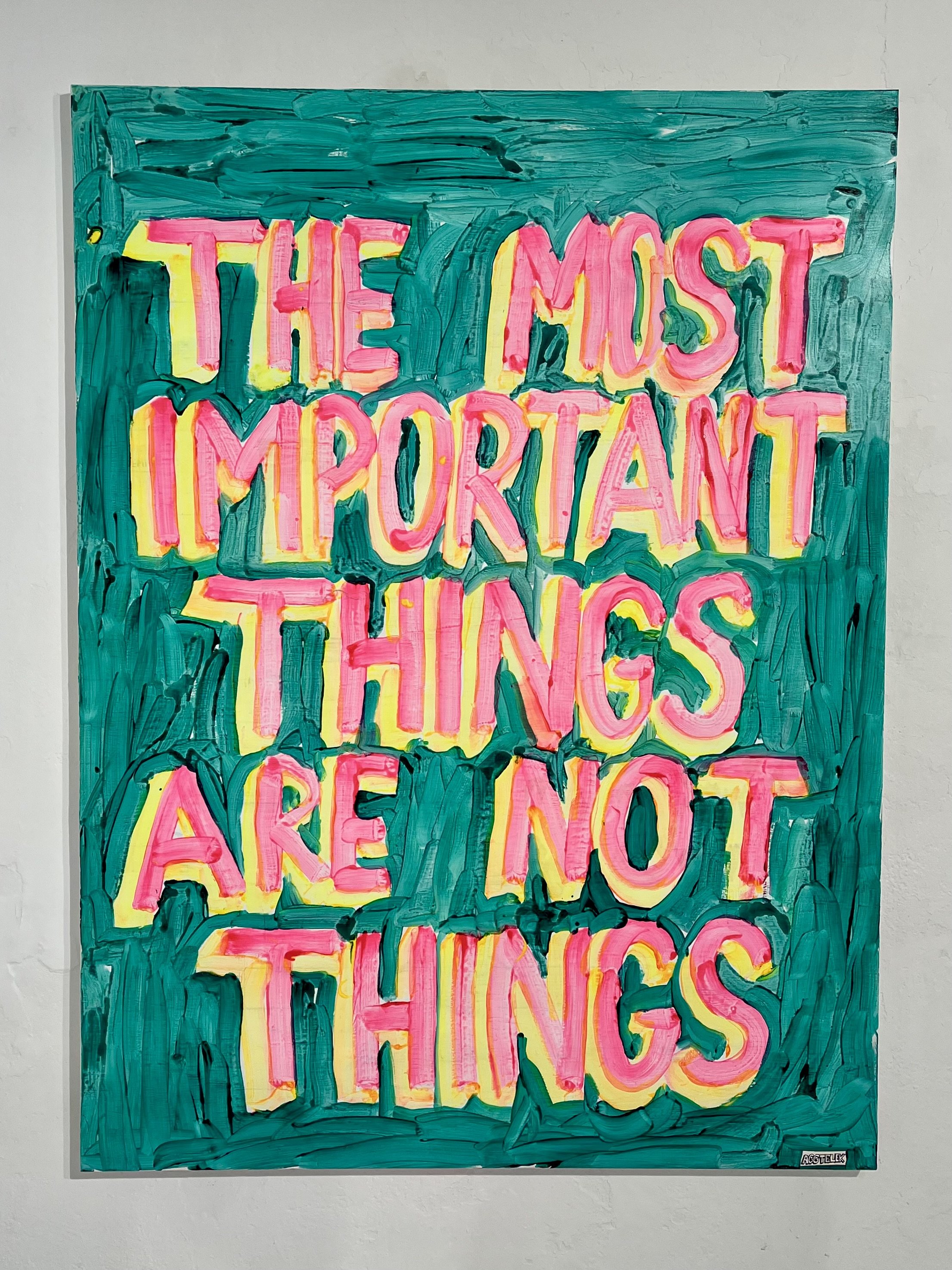 Colorful graffiti-style painting with the phrase "The Most Important Things Are Not Things" in pink and yellow letters on a green background.