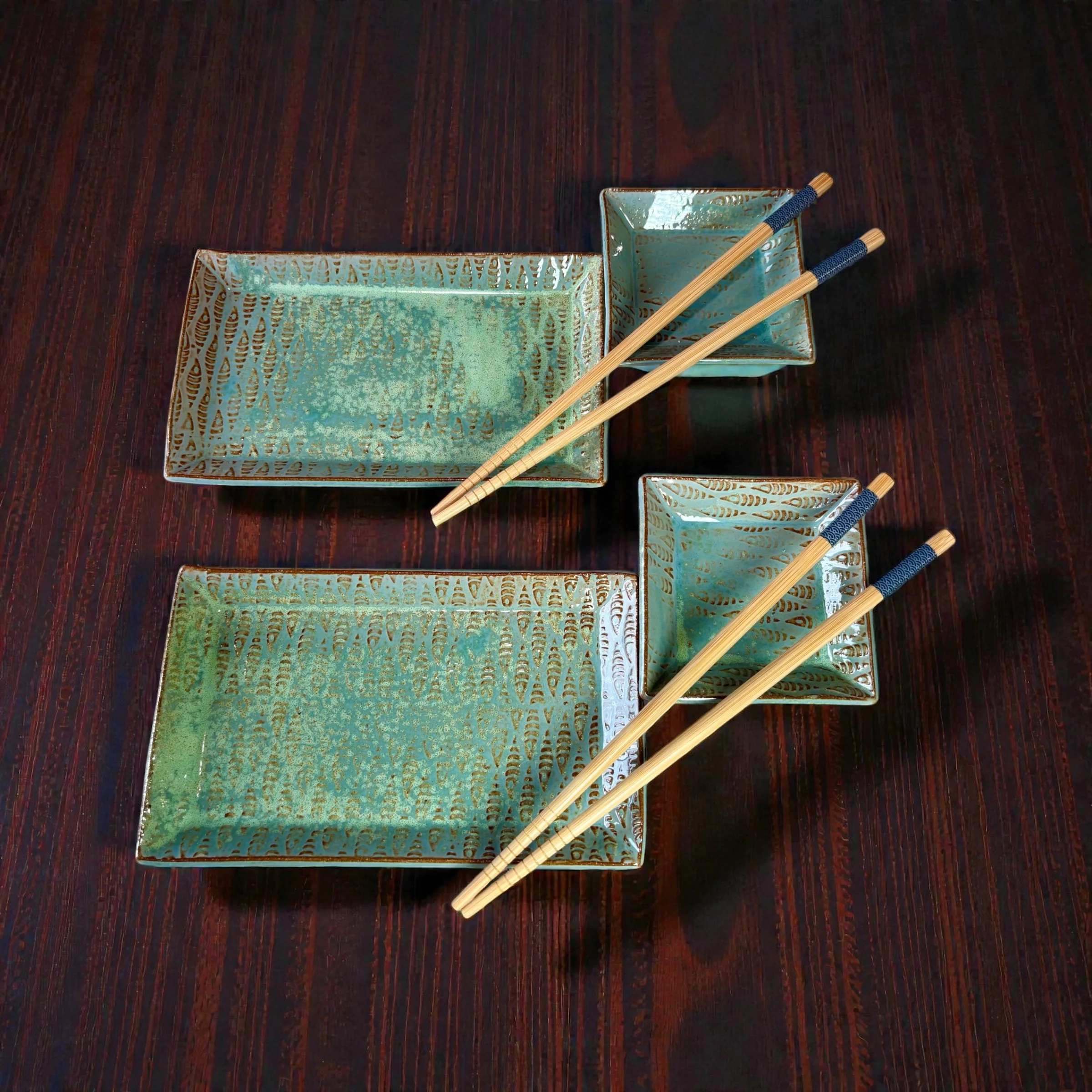 Set of decorative teal and gold rectangular and square dishes, each paired with wooden chopsticks on a dark wooden table.