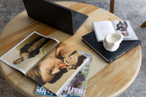 Flatlay of magazines and a laptop on a timber table