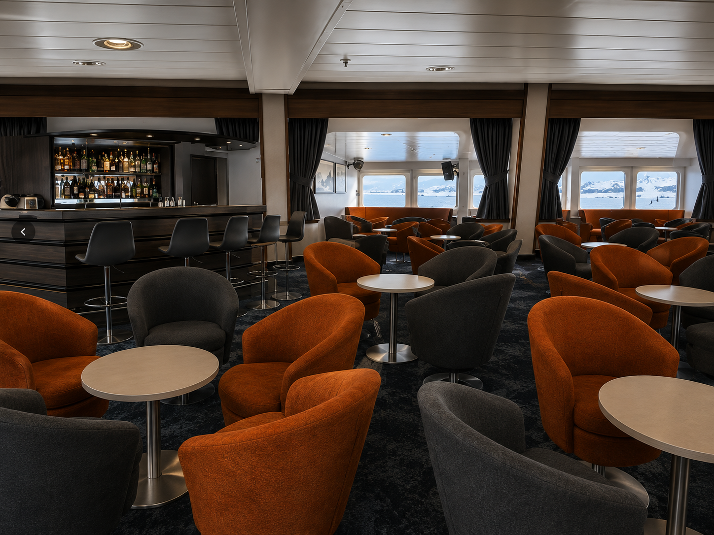 Lecture lounge and bar aboard Terra Nova Adventurer, with armchairs facing large windows
