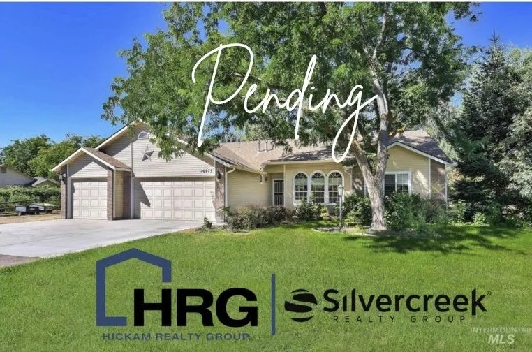 Front view of a yellow house with three-car garage, large tree in front yard, and green lawn under clear blue sky.