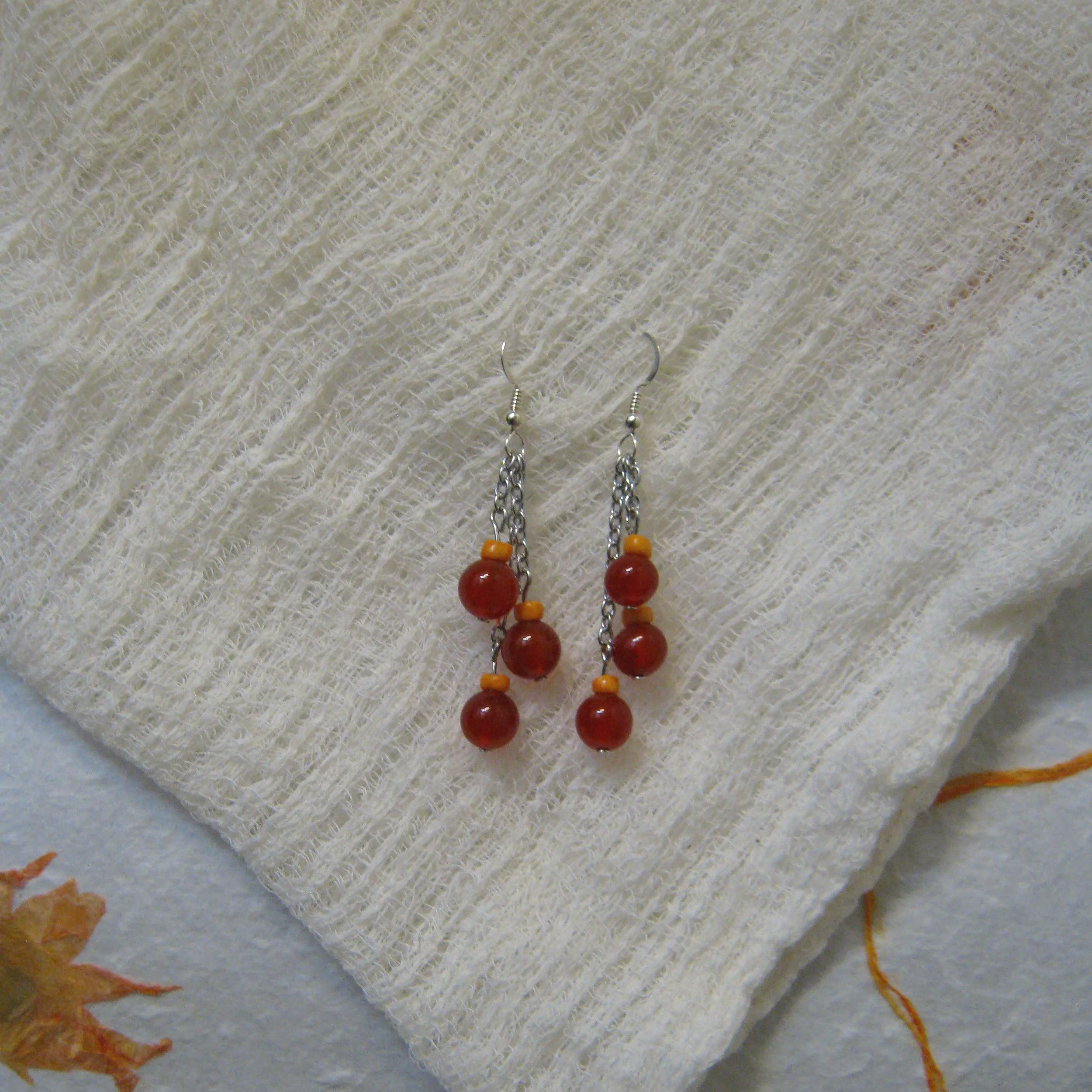 Carnelian & Orange Bead Dangle Trio Earrings - $12 | Carnelian is known for being a stone of courage, endurance, energy, leadership, and motivation. It also helps you grow confidence and boosts your creativity. Carnelian is very grounding, helping to