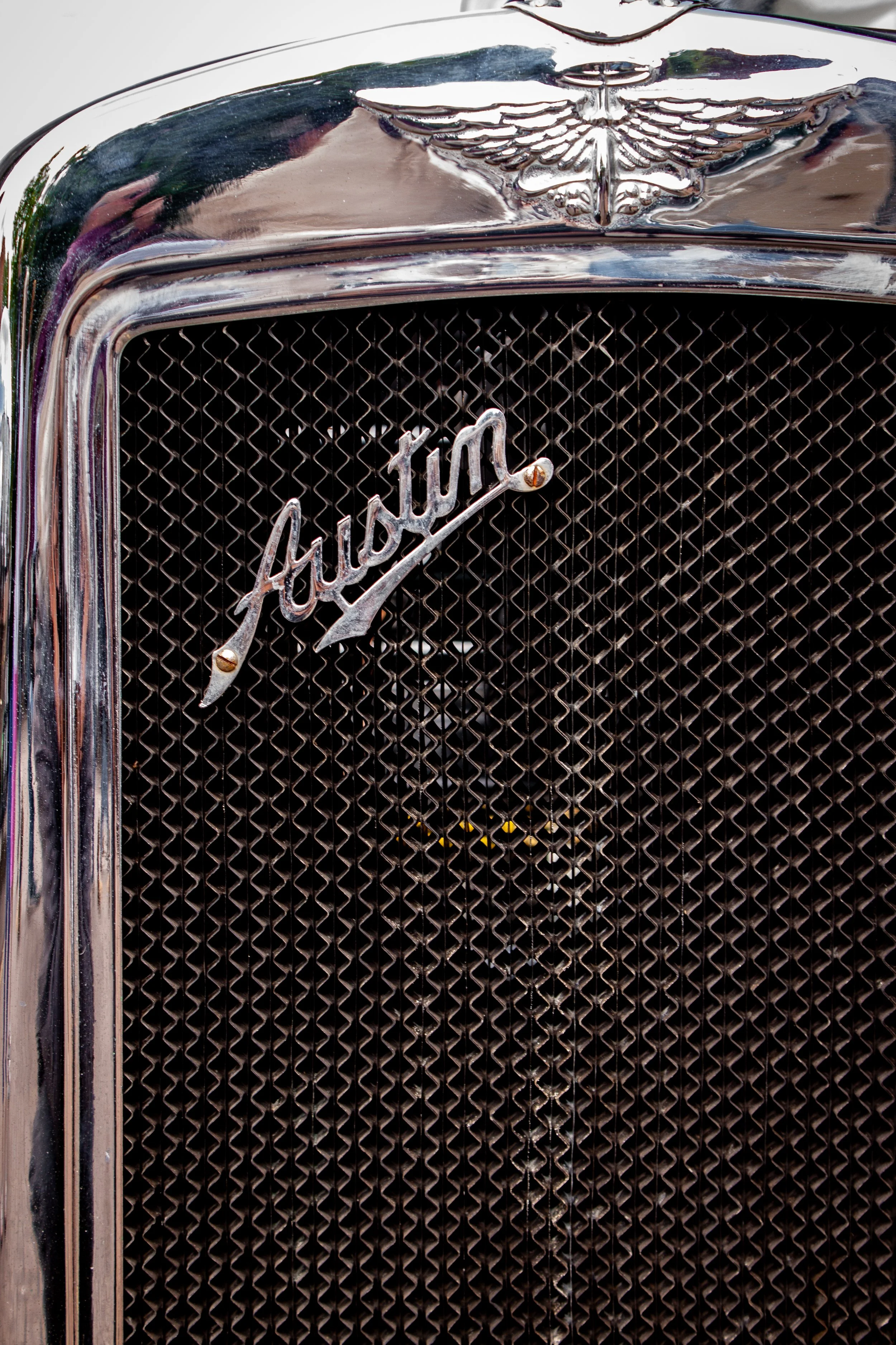 Close-up of a vintage Auburn automobile grille with a chrome Auburn emblem and eagle hood ornament.