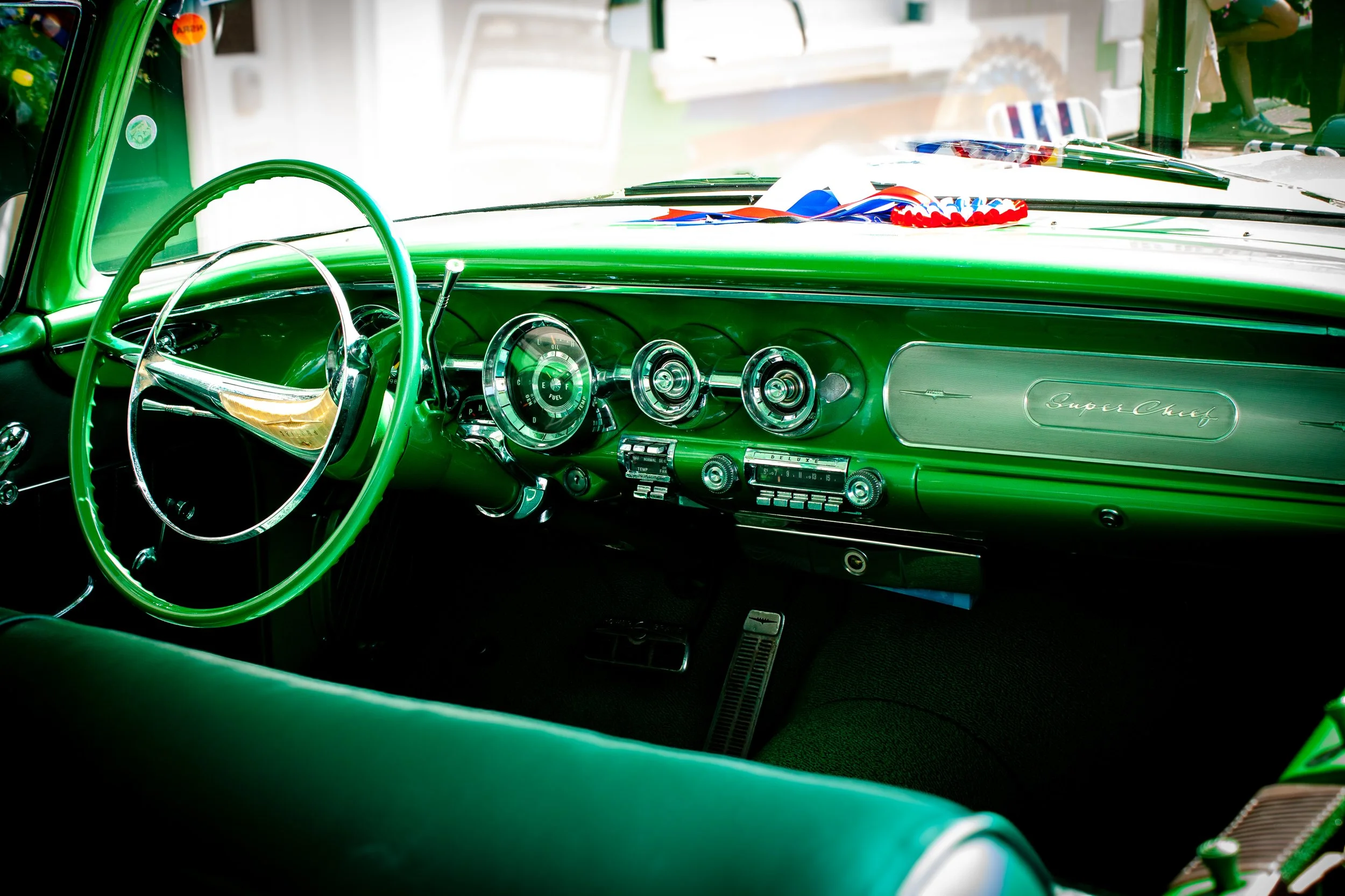 Interior of a vintage green Chevrolet Super Chief car with chrome gauges and steering wheel.