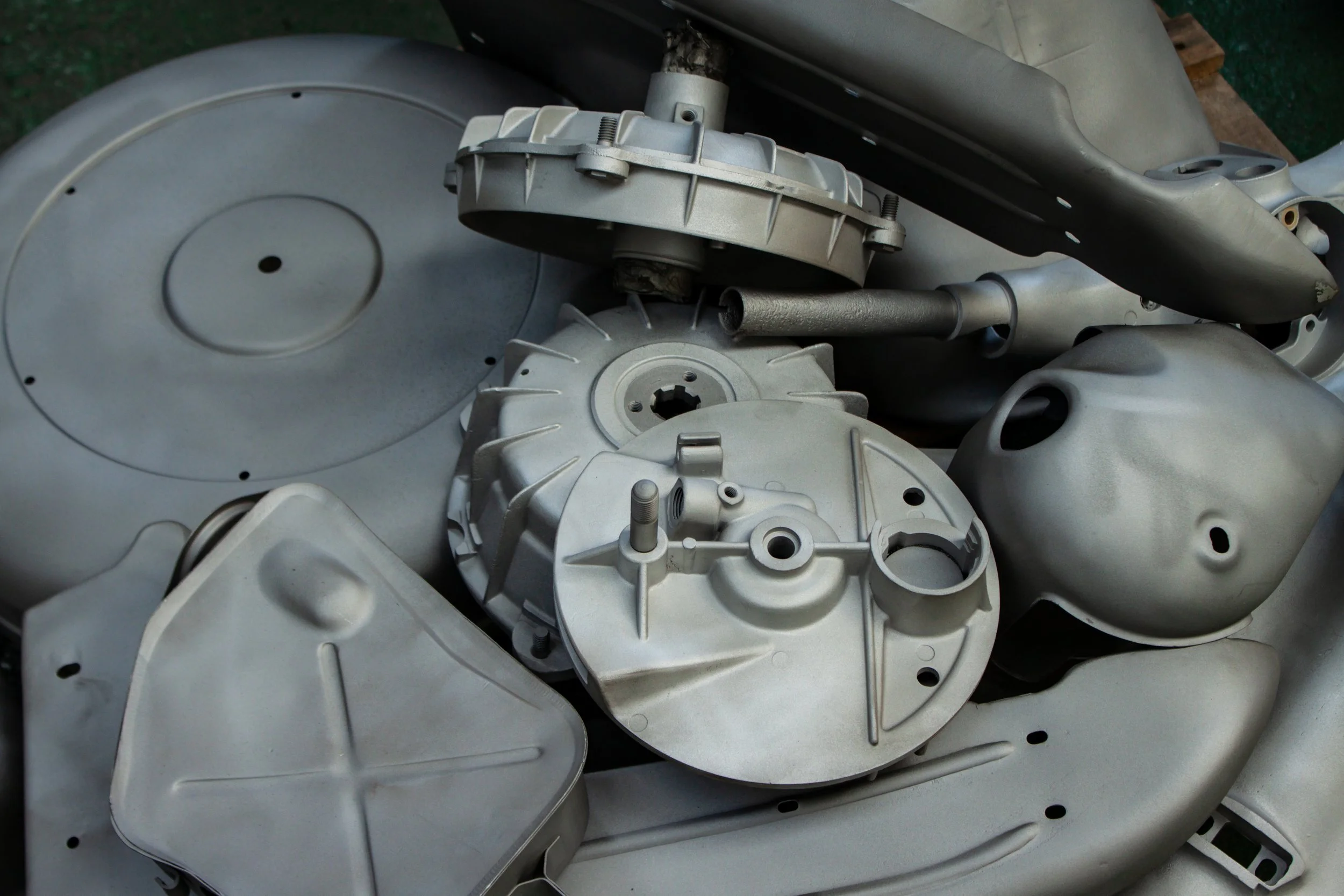 Multiple disassembled metallic parts, possibly from a mechanical or engine assembly, arranged on a surface.