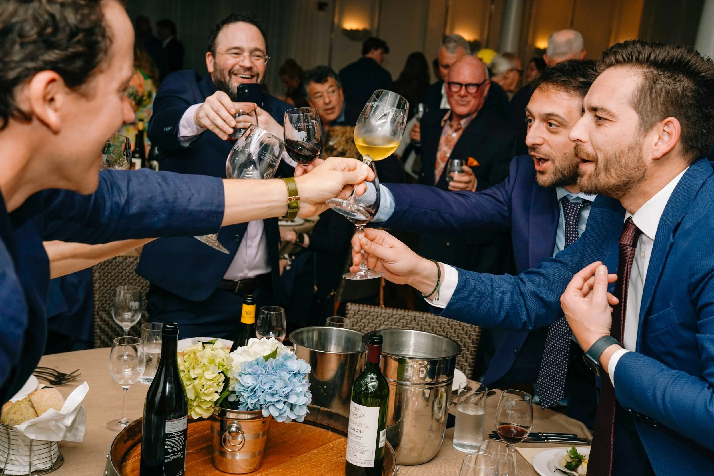 People celebrating and clinking glasses of wine and champagne at a formal event or party.
