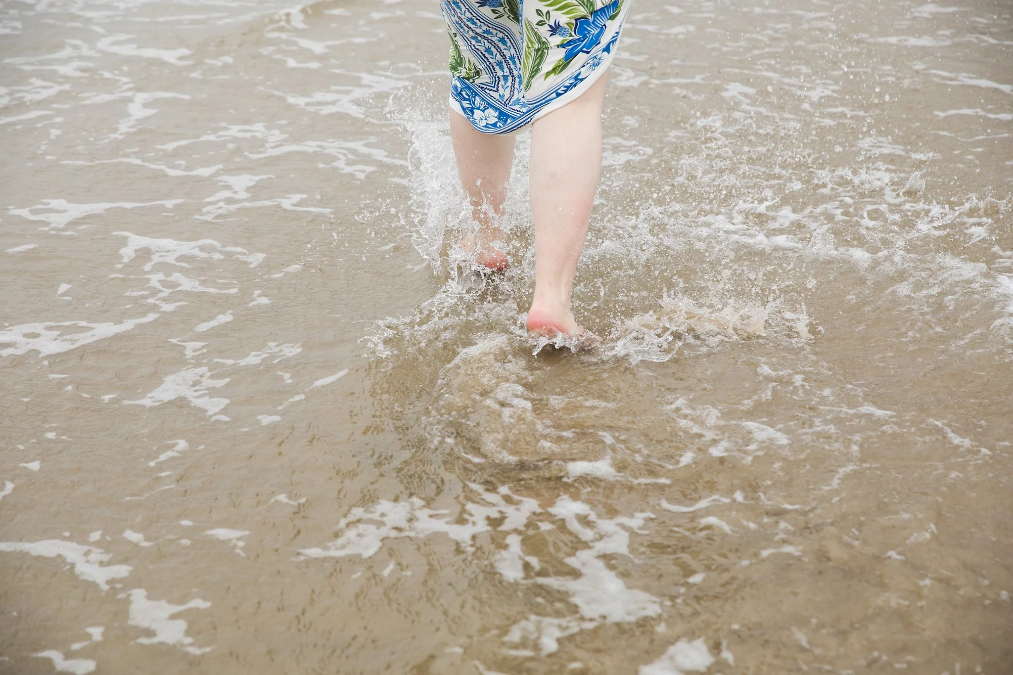 Woman with colorful dress walking on the beach.
