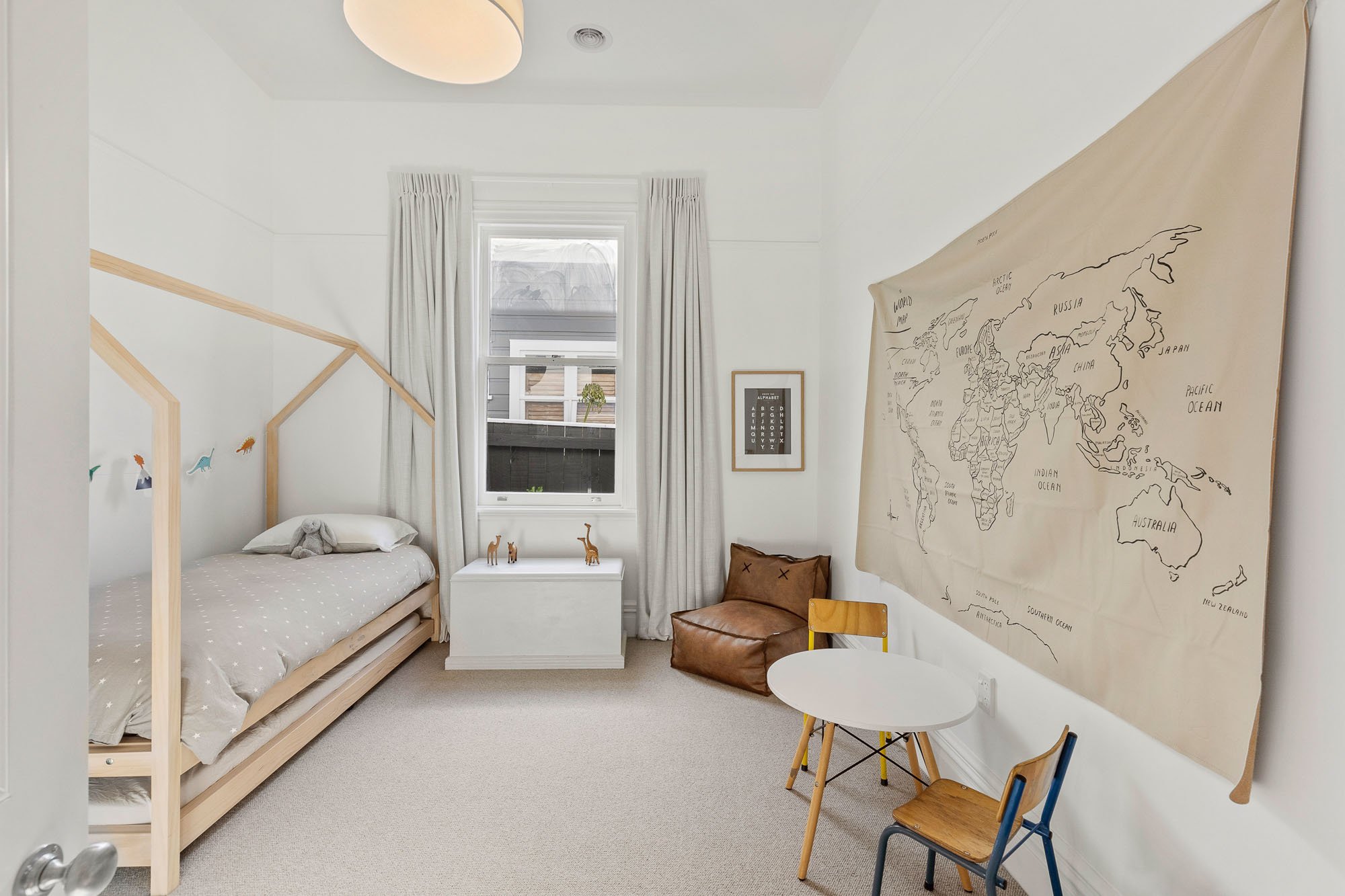 Children’s bedroom with a wooden bed shaped like a house, a world map on the wall, this Wellington hose was renovated after a design by Kate Harford from Lower Hutt architectural firm, Hark Architects