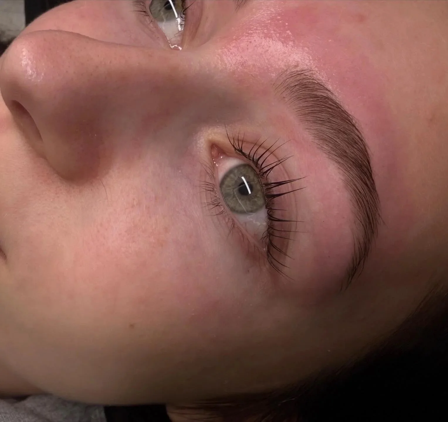 Close-up of a person's face showing their nose, eye, and eyebrow with long eyelashes.