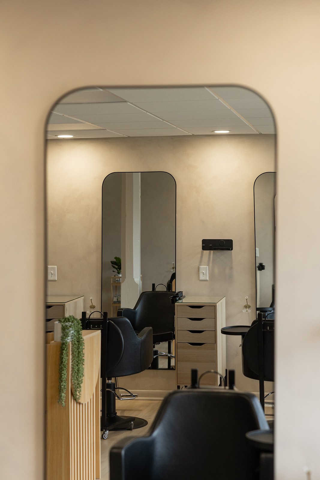 Interior of a hair salon with mirrors, black chairs, and wooden storage units