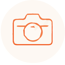 Icon of a camera in orange outlines over a white circular background.