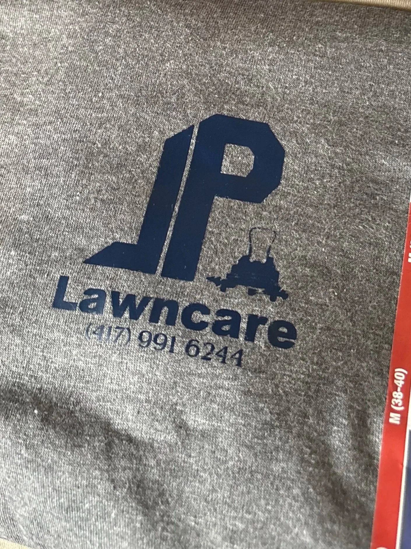 Gray fabric surface with a blue logo of a dog and the text 'LawnsCare' below it, along with a phone number.