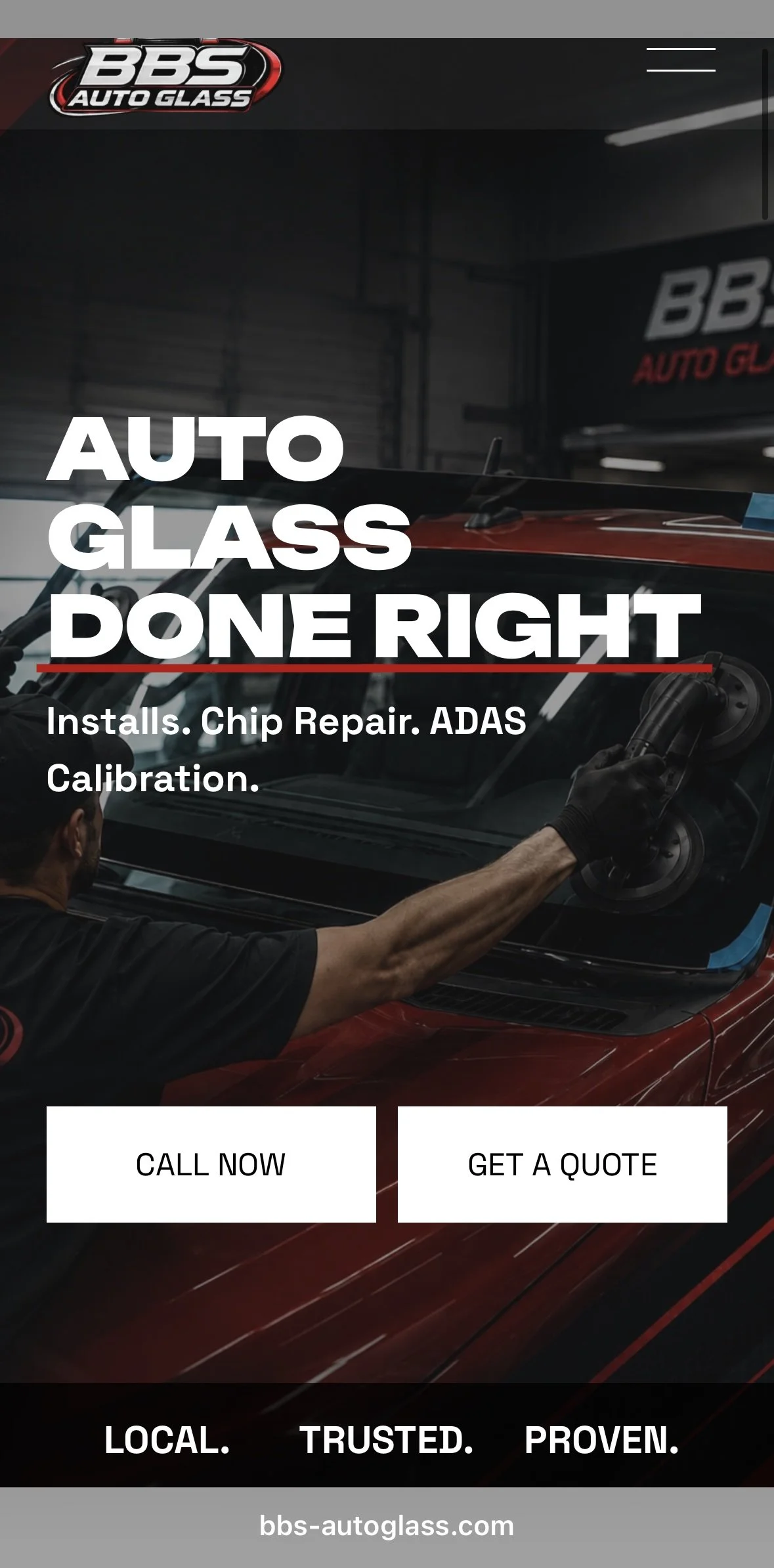 A person working on the windshield of a red car inside an auto repair shop, with the shop's signage visible that reads 'BBS Auto Glass'.