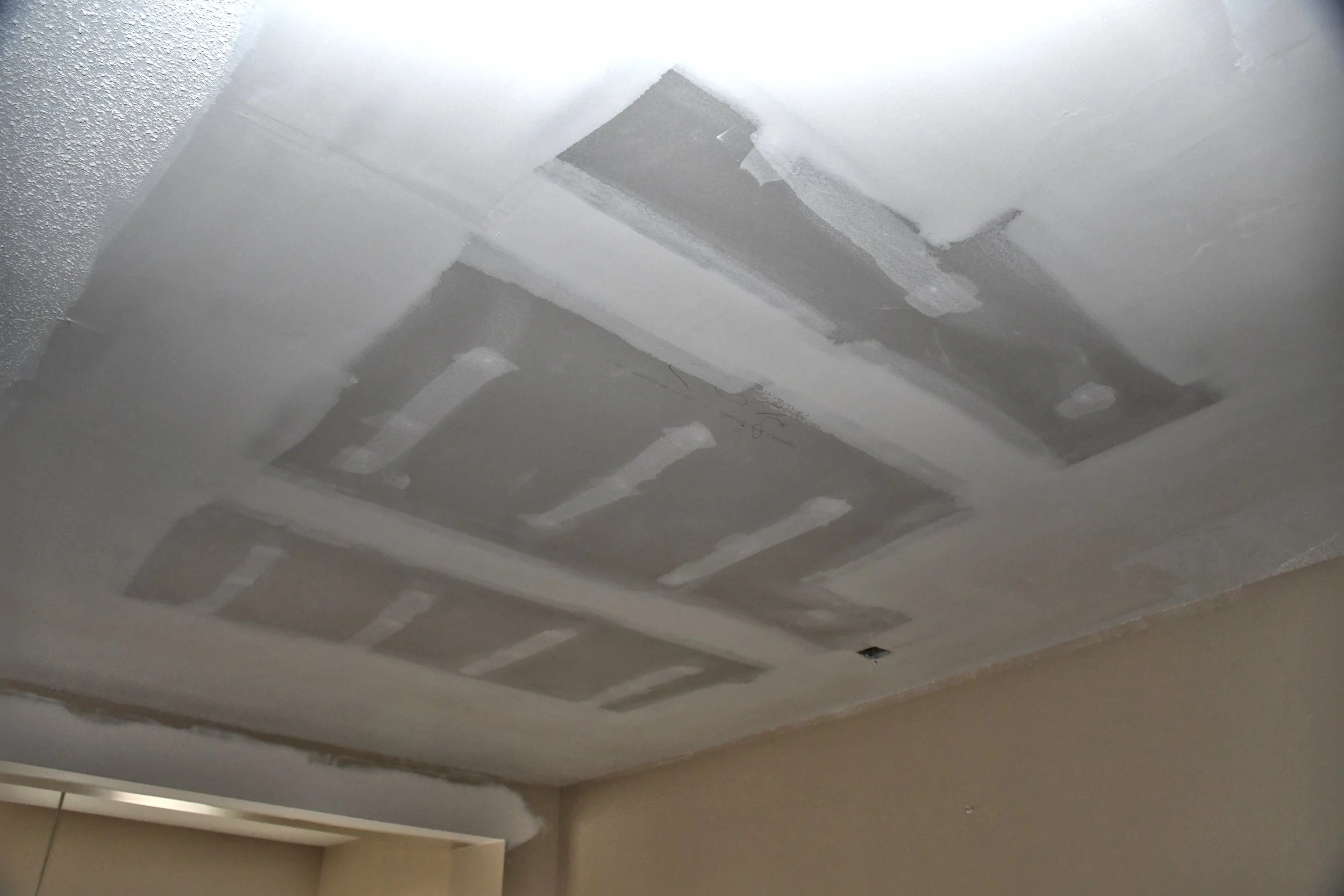 Ceiling with drywall patches and sanding marks from drywall installation or repair.